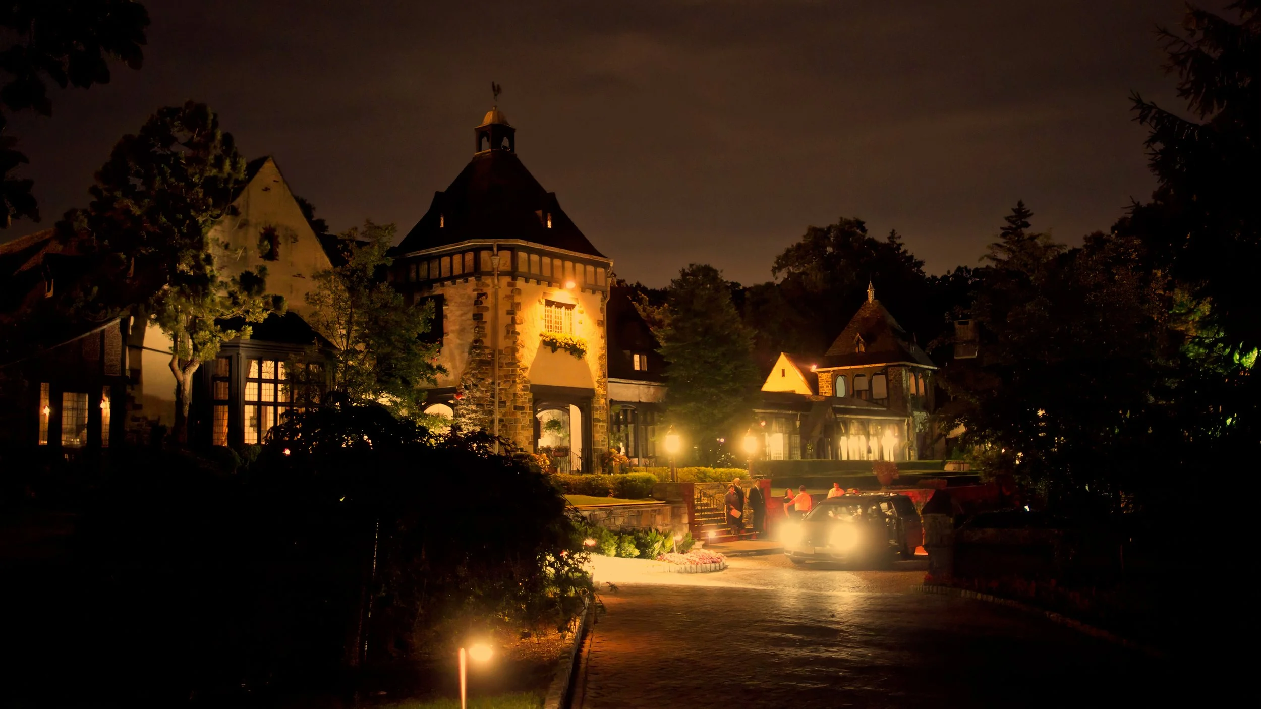 Pleasantdale Chateau illuminated at night as wedding guests depart after the celebration.