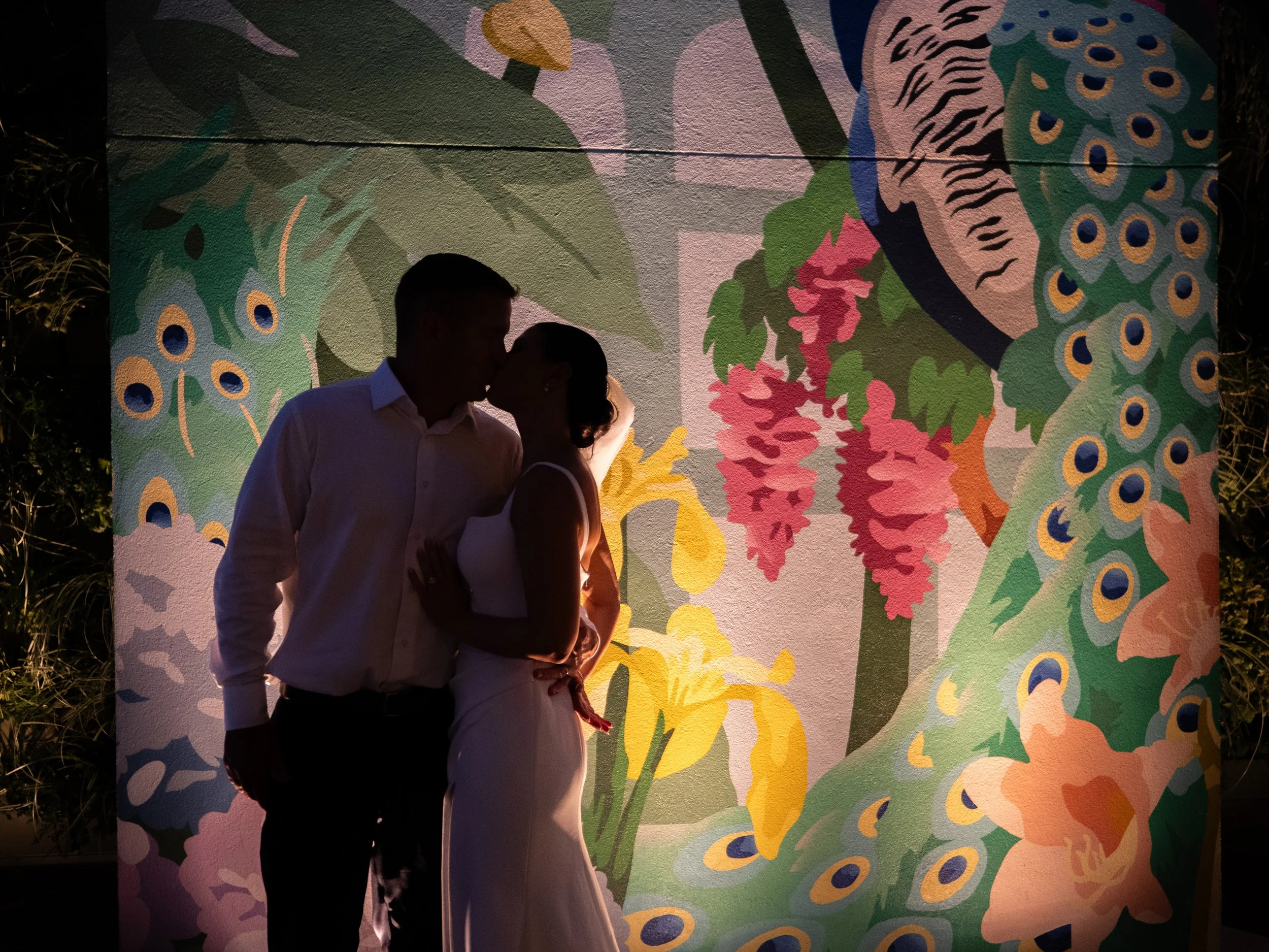 Silhouette of Kate and Ryan kissing against the colorful mural on the Perry Lane rooftop