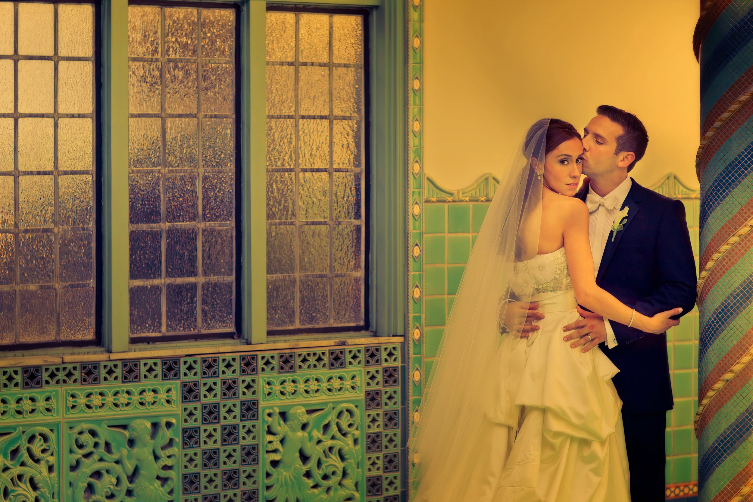 Groom kisses the bride beside the indoor pool at Pleasantdale Chateau in a romantic editorial style portrait.