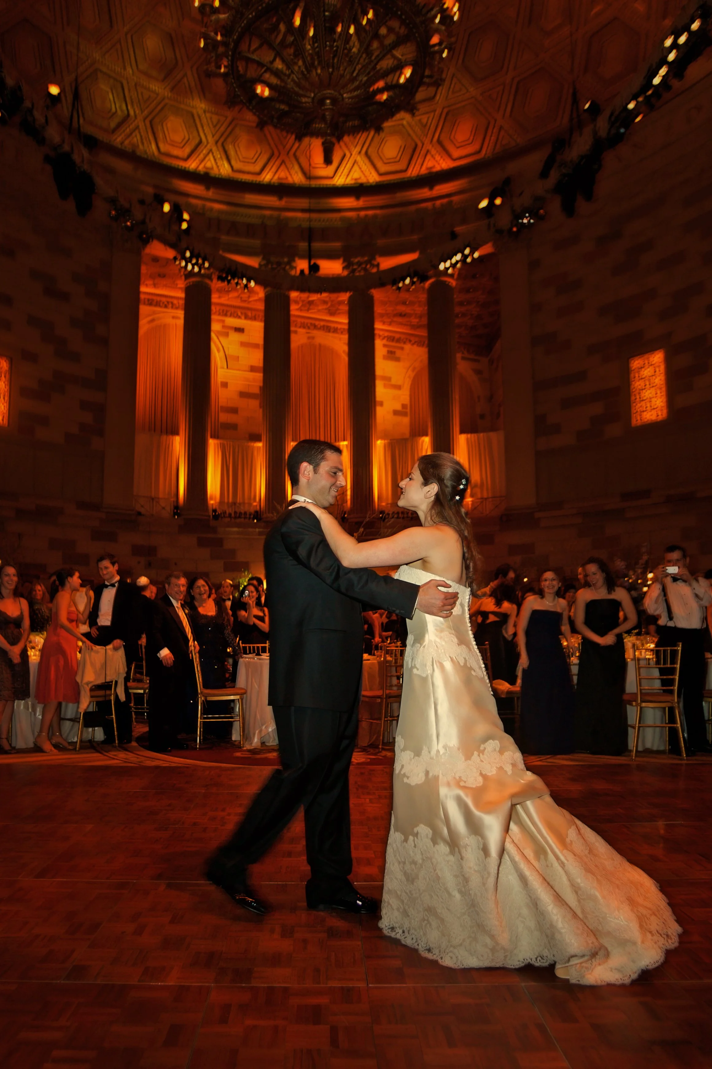 Bride and groom share their first dance beneath the grand dome of Gotham Hall during their wedding reception.