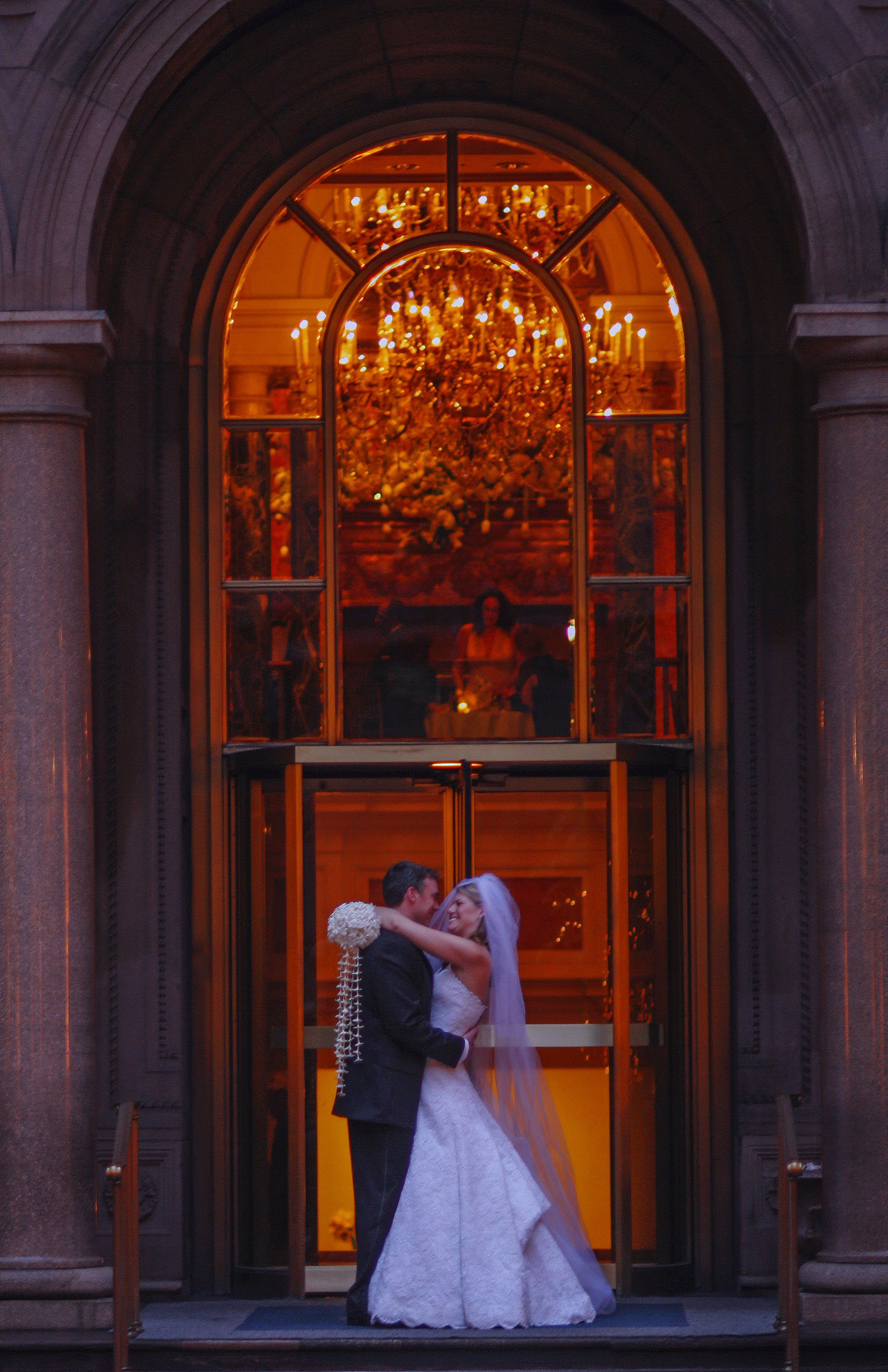 Bride and groom embracing in the courtyard of Lotte New York Palace Hotel at evening