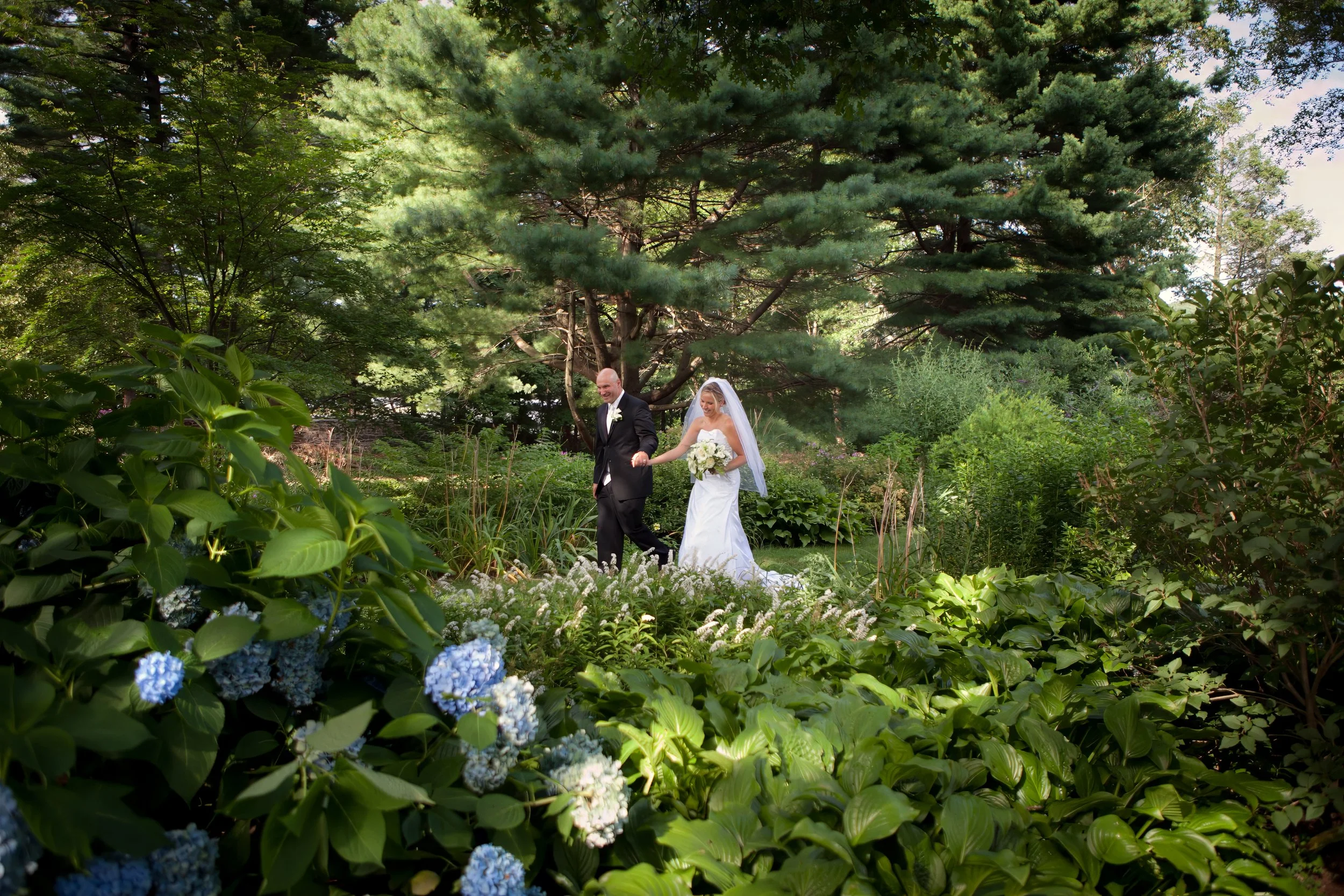 Bride and groom walking the landscaped grounds at The Woodwinds in Branford, Connecticut.