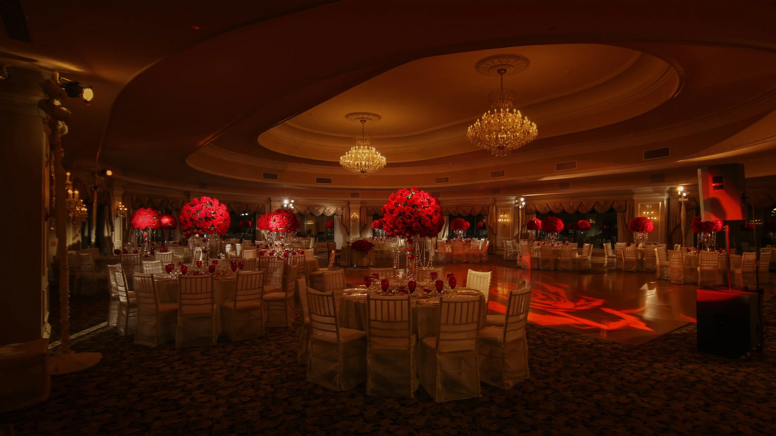Grand ballroom at Oheka Castle decorated with lavish rose floral centerpieces for a wedding reception.