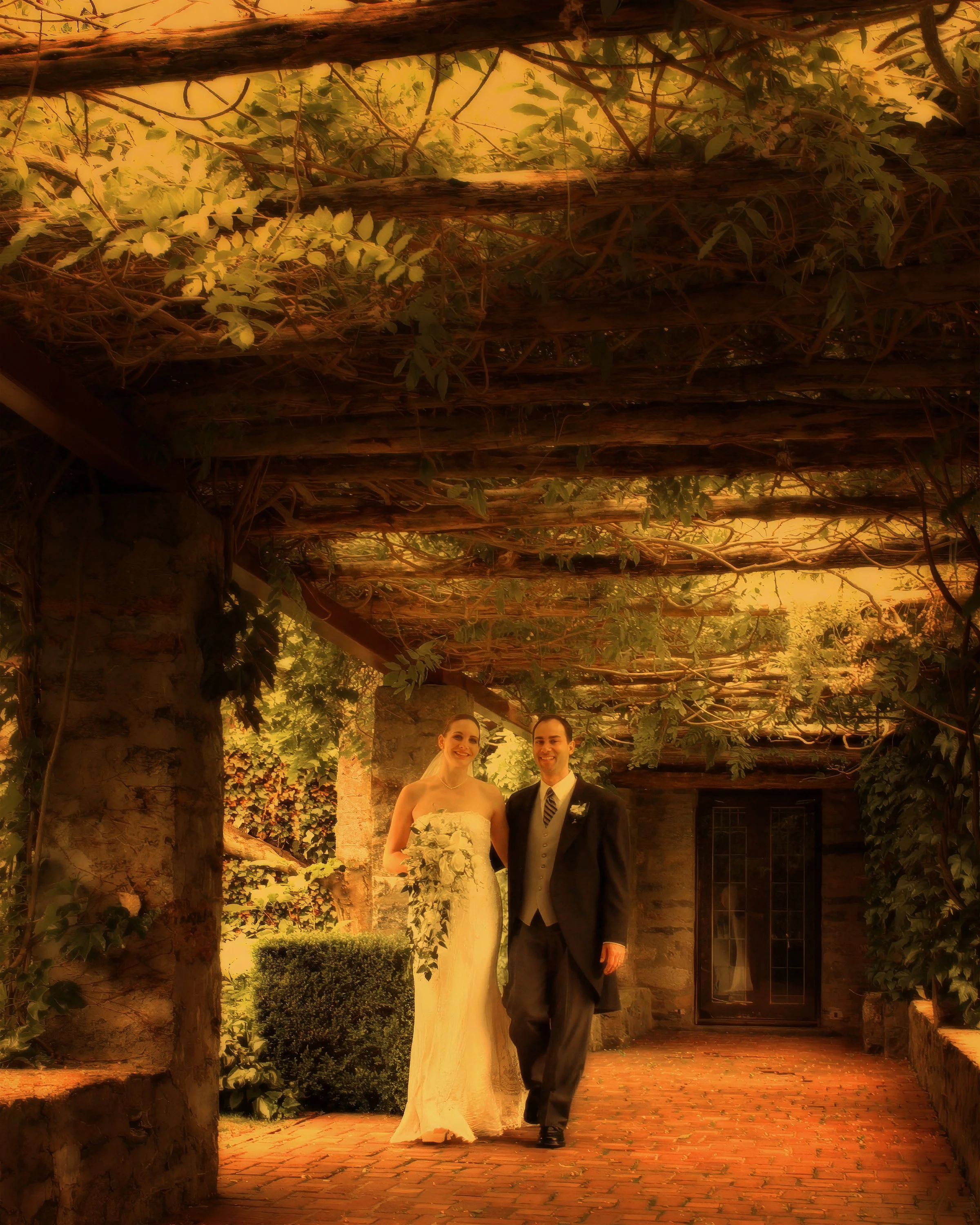 Bride and groom walking beneath the arbor at Saint Clements Castle during a spring wedding
