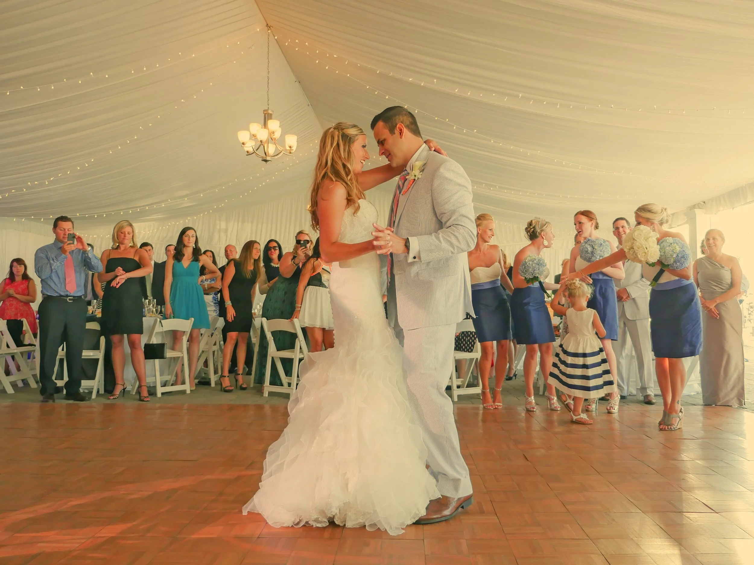 Wide angle photograph of a bride and groom sharing their first dance under the sailcloth tent at The Bohlin in Newport.
