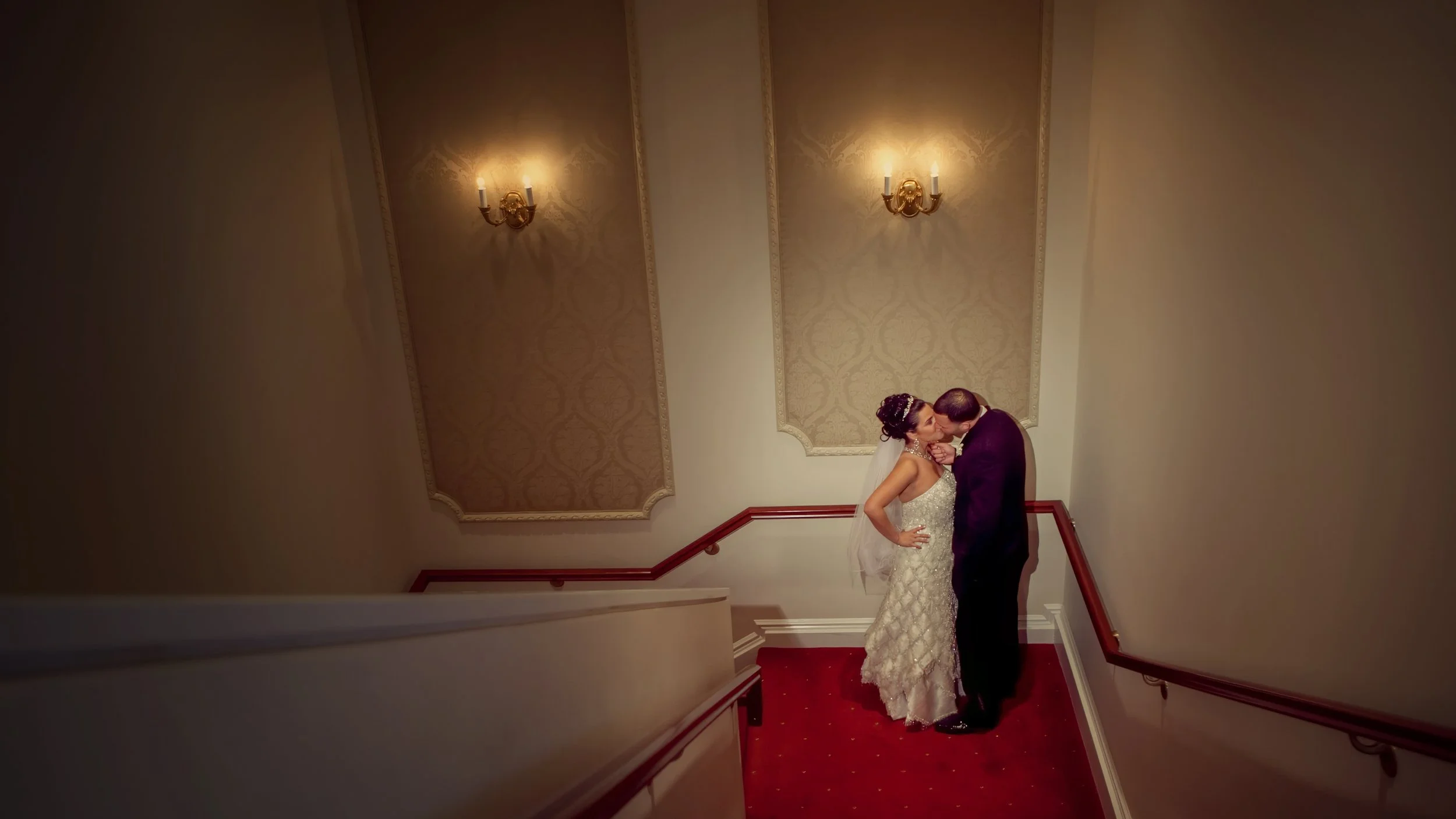 Bride and groom share a kiss on the red-carpeted staircase at The Palace at Somerset Park.