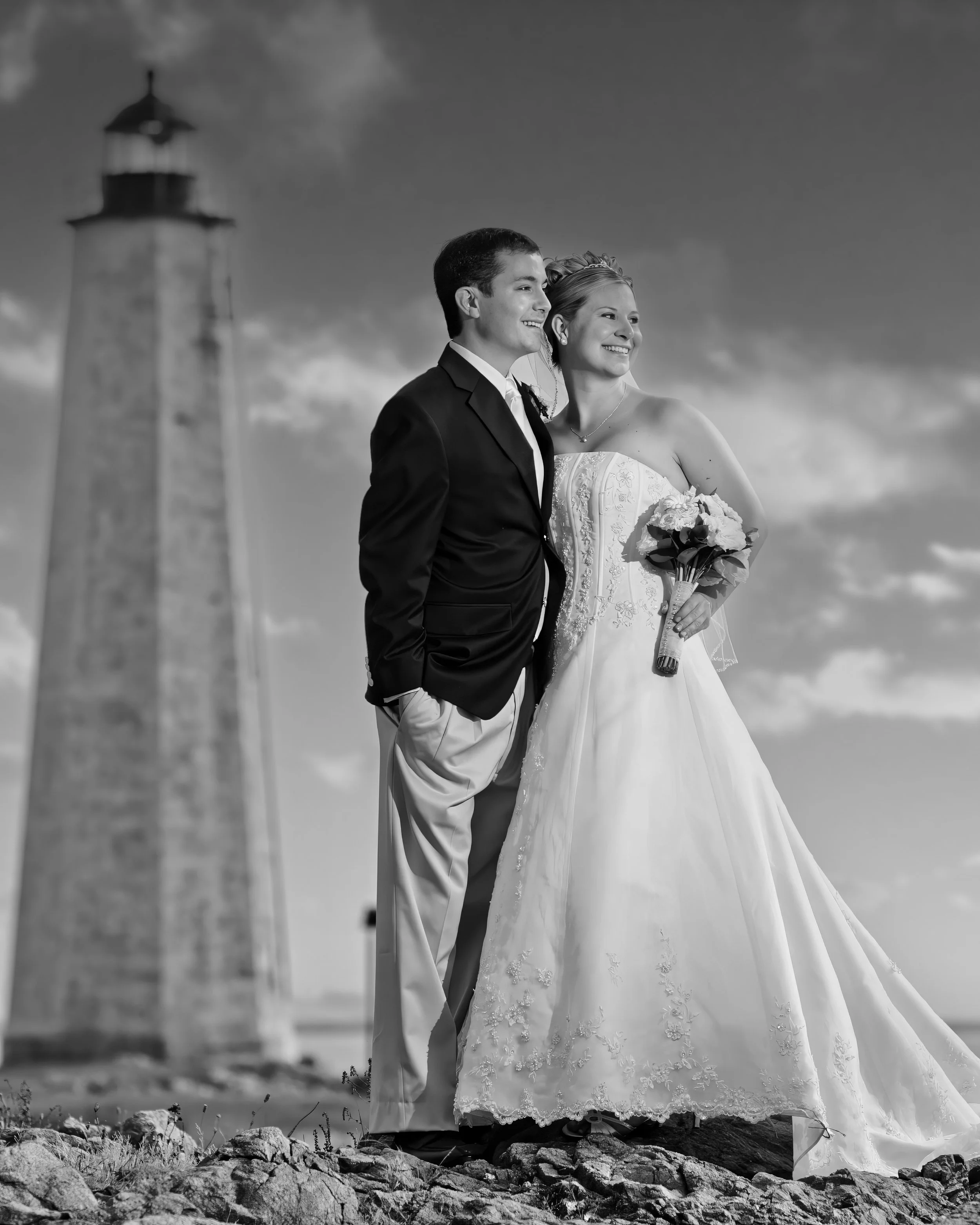 Majestic portrait of bride and groom with Lighthouse Point Park lighthouse in the distance in New Haven Connecticut