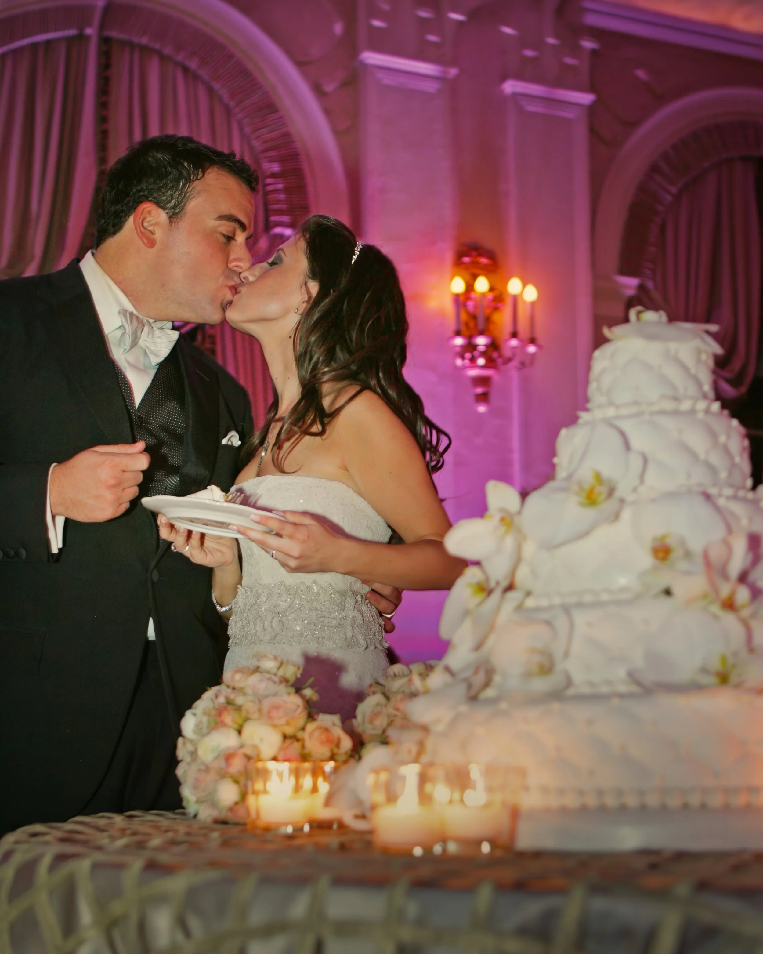 Bride and groom kiss after cutting their wedding cake at the Yale Club