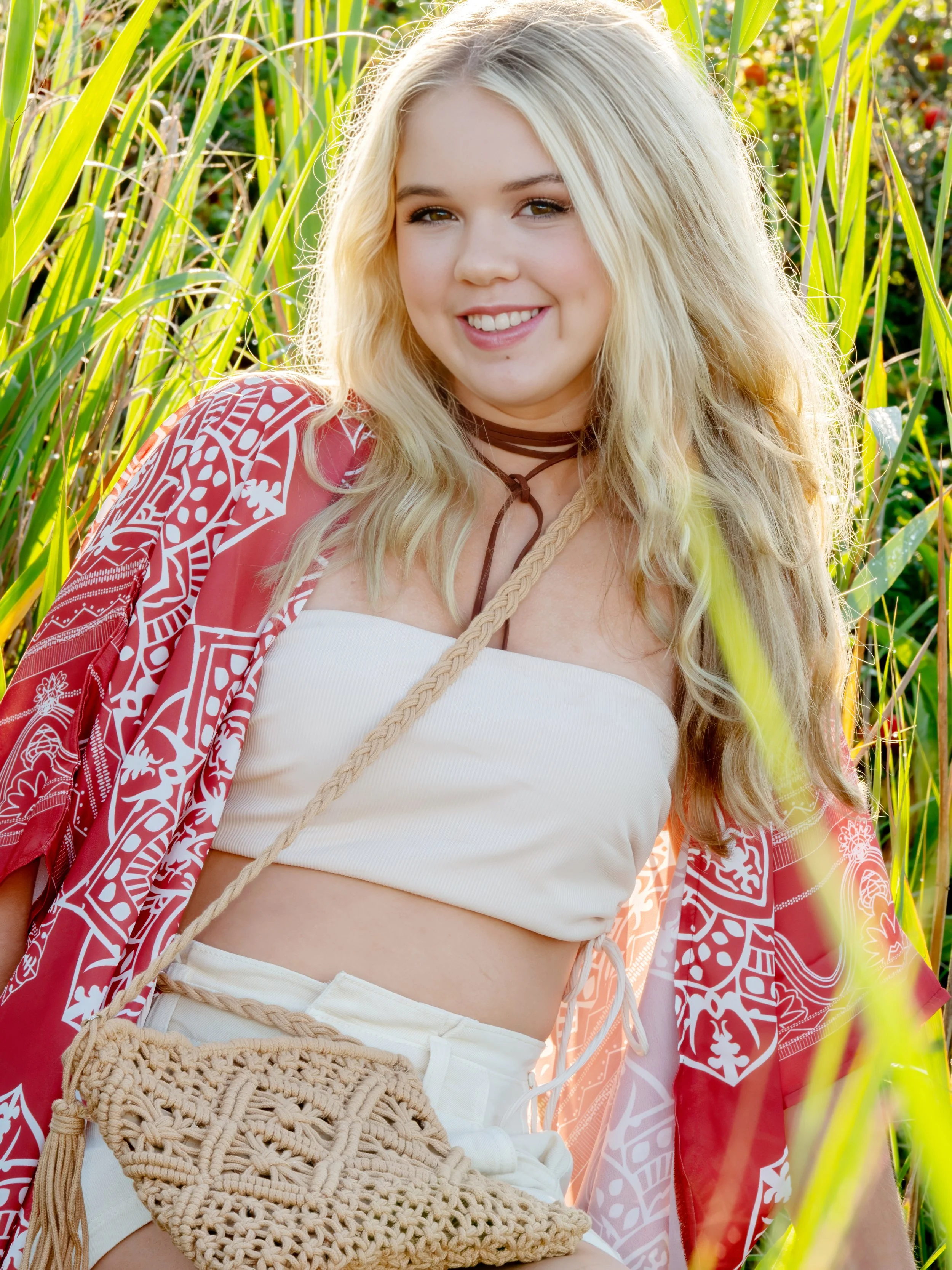 Senior portrait of a young adult on the sand dunes along the Connecticut shoreline, with soft natural light highlighting her face.