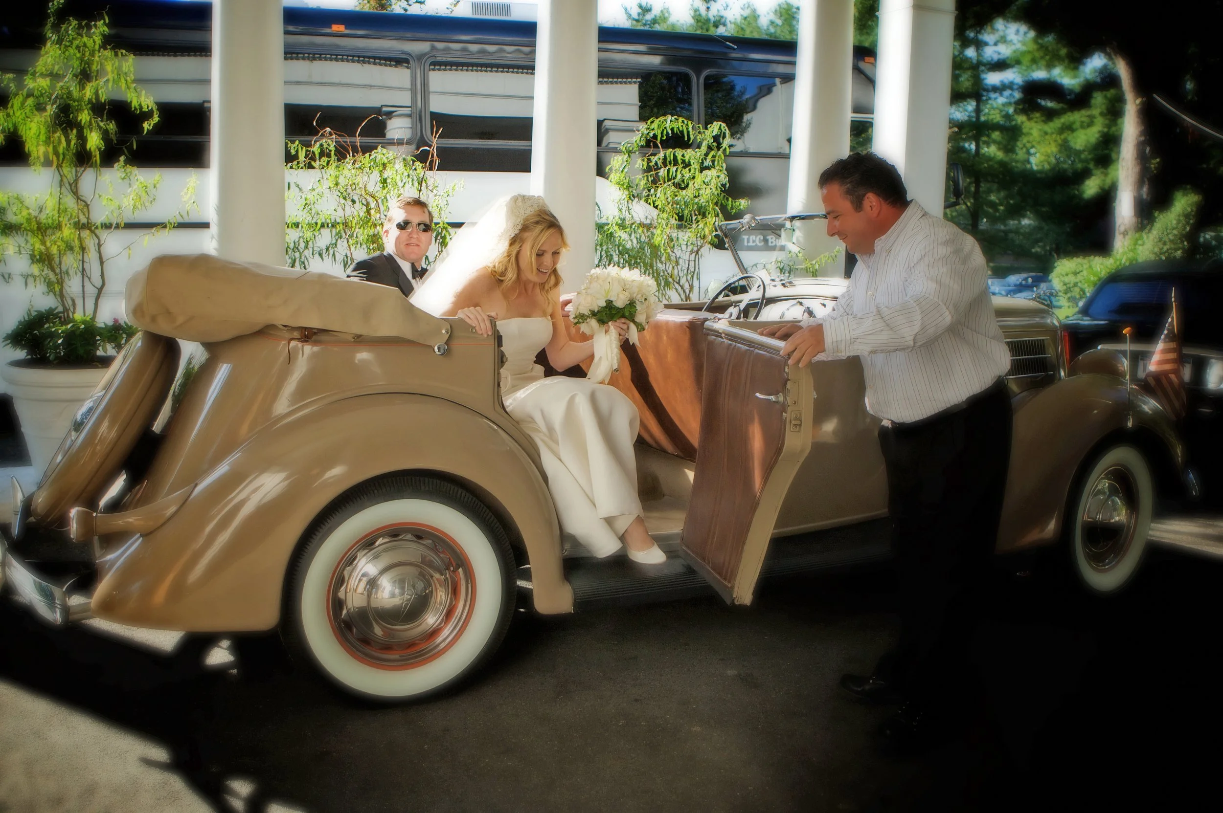 Bride and groom step out of a vintage car at the entrance of Siwanoy Country Club in Westchester.
