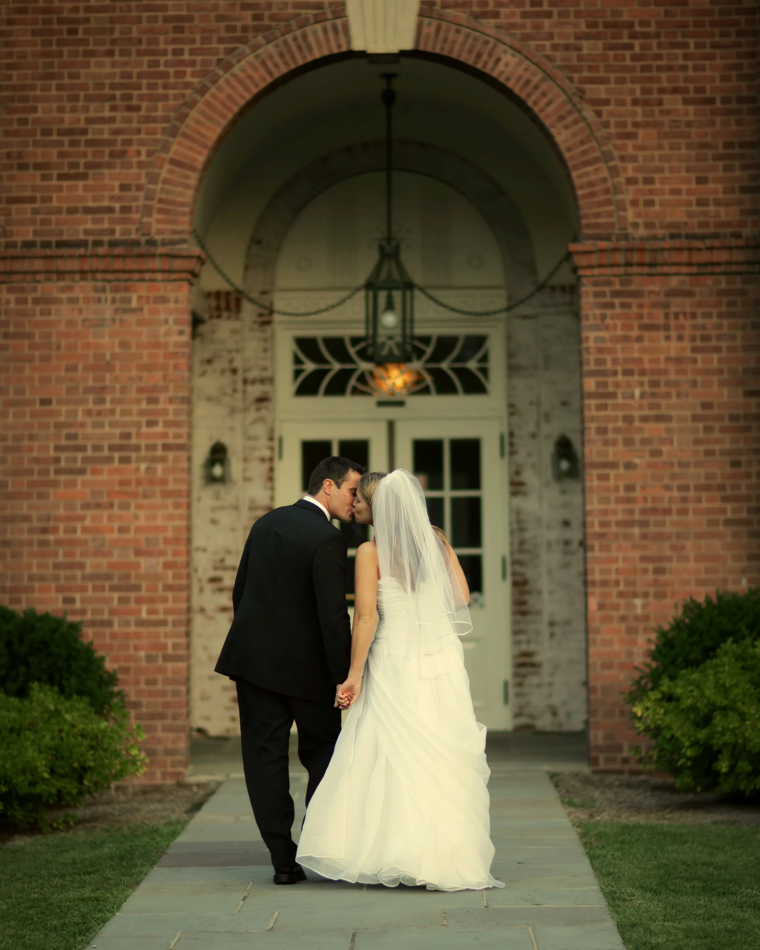 Bride and groom kiss as they enter the New Haven Lawn Club for their wedding celebration.