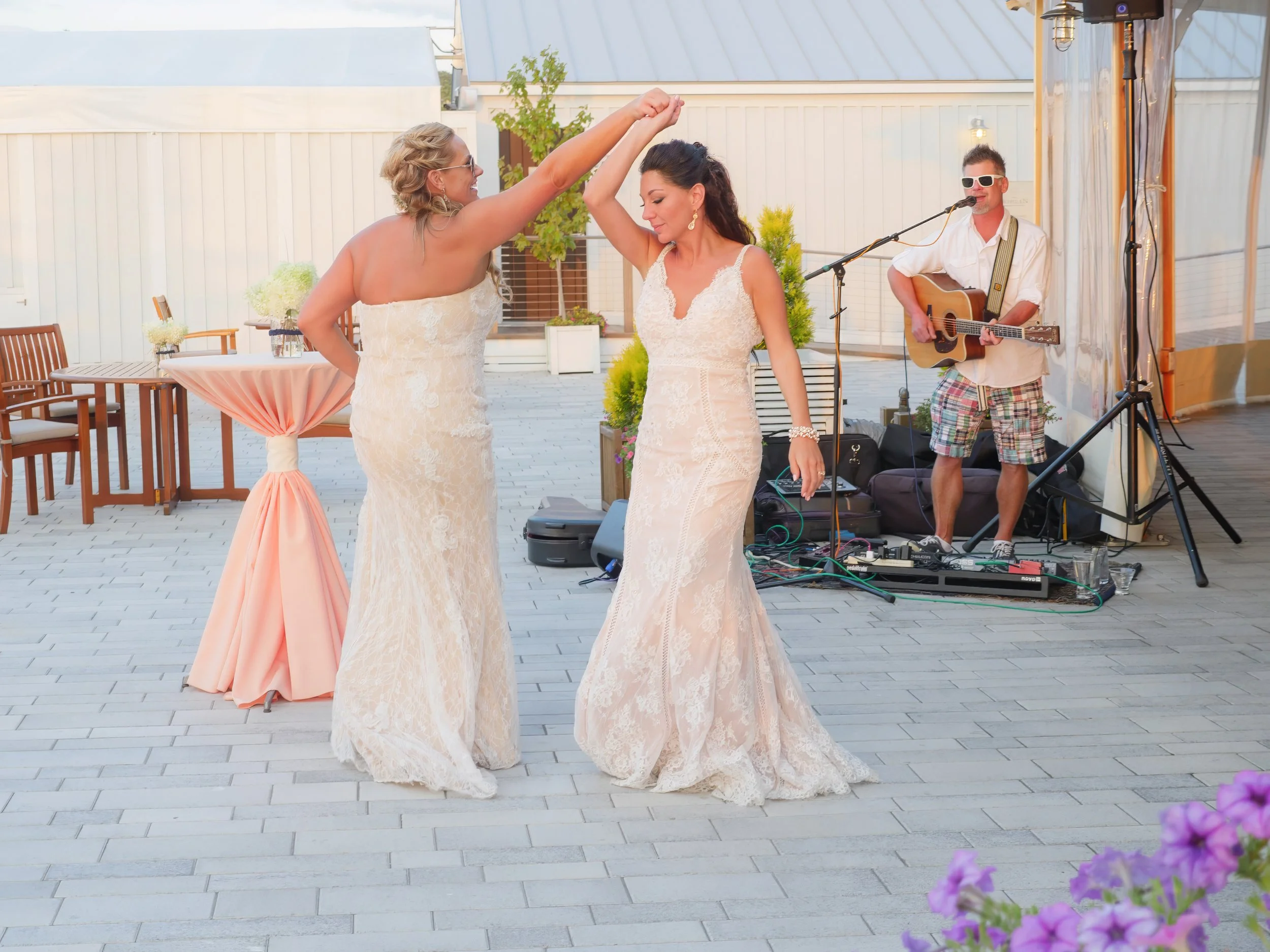 A wedding couple dance while a musician performs during cocktail hour on the patio at Newport Yachting Center.