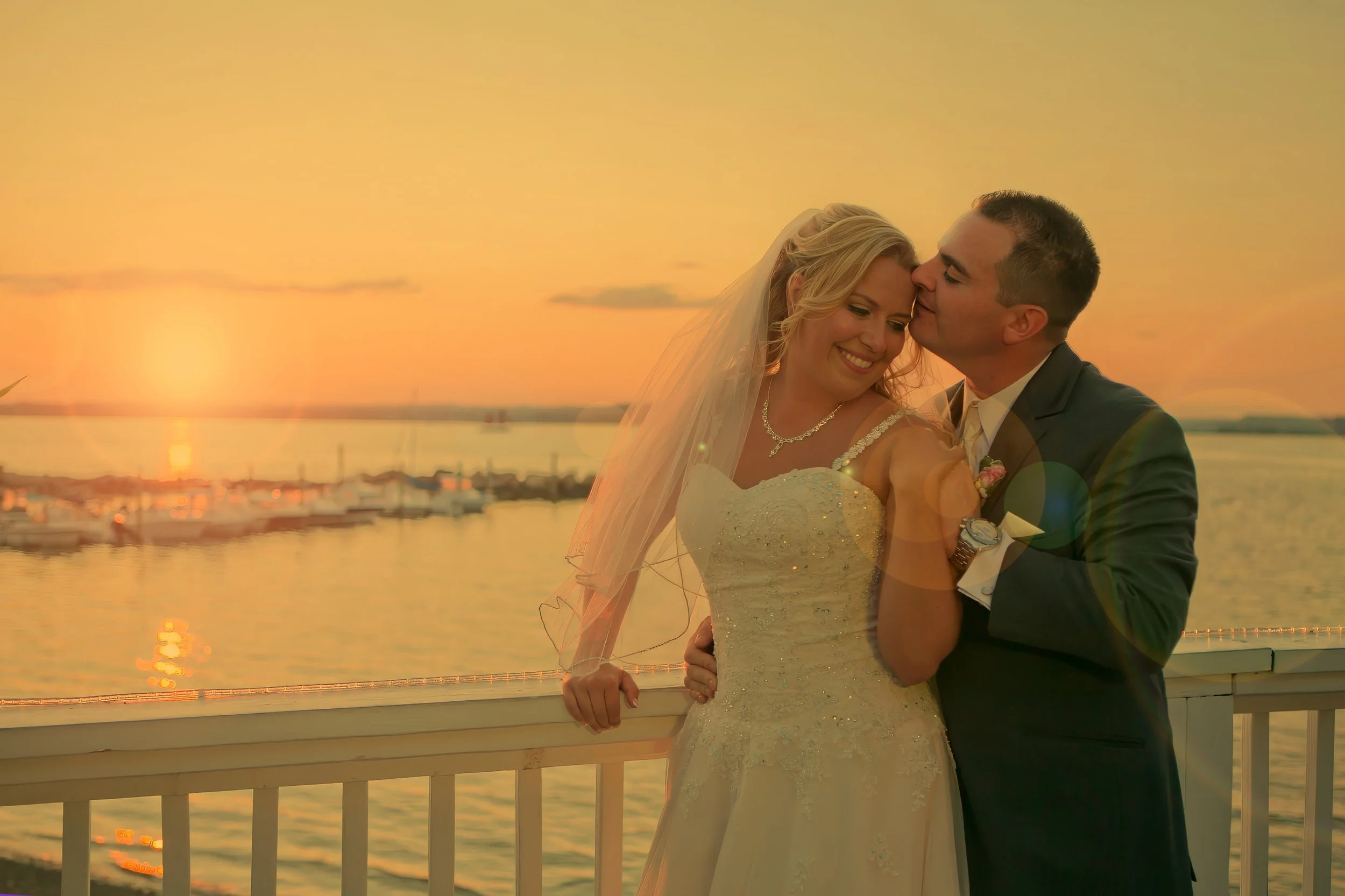 Bride and groom share a soft moment on the deck at Amarante’s Sea Cliff overlooking the marina at sunset