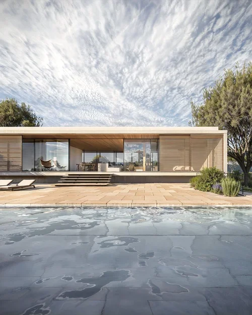 Vivienda unifamiliar de una planta con fachada de lamas de madera, grandes ventanales y piscina integrada en el jardín.
