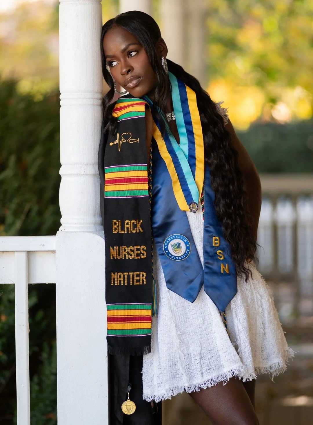 College graduate posing outdoors in graduation honors and stole