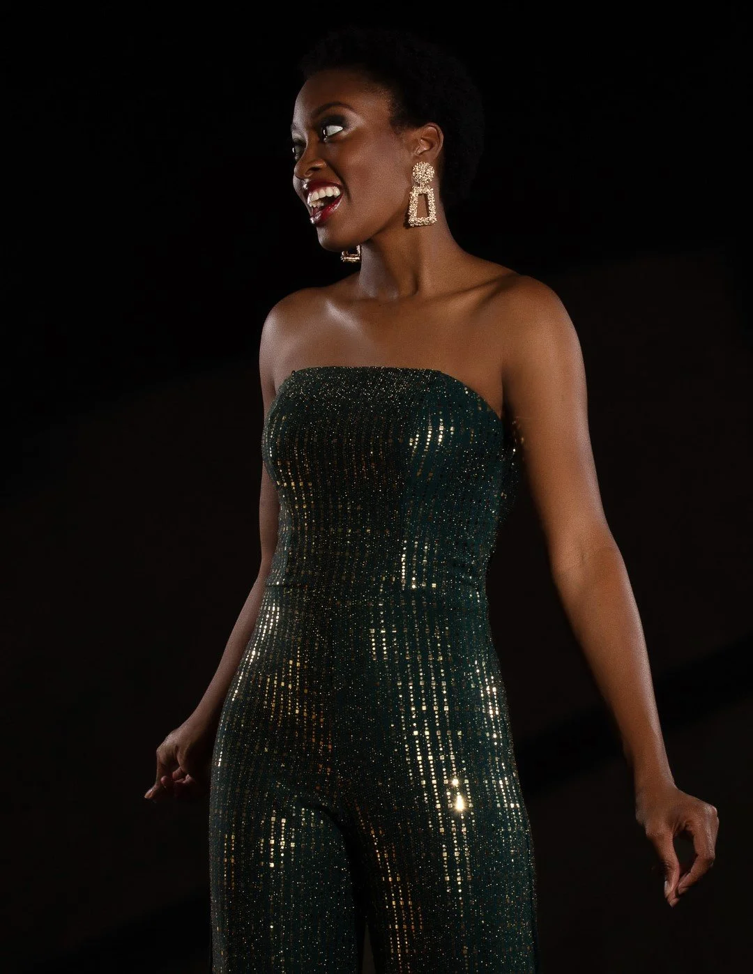Creative studio portrait of a woman in a dark green sequined jumpsuit