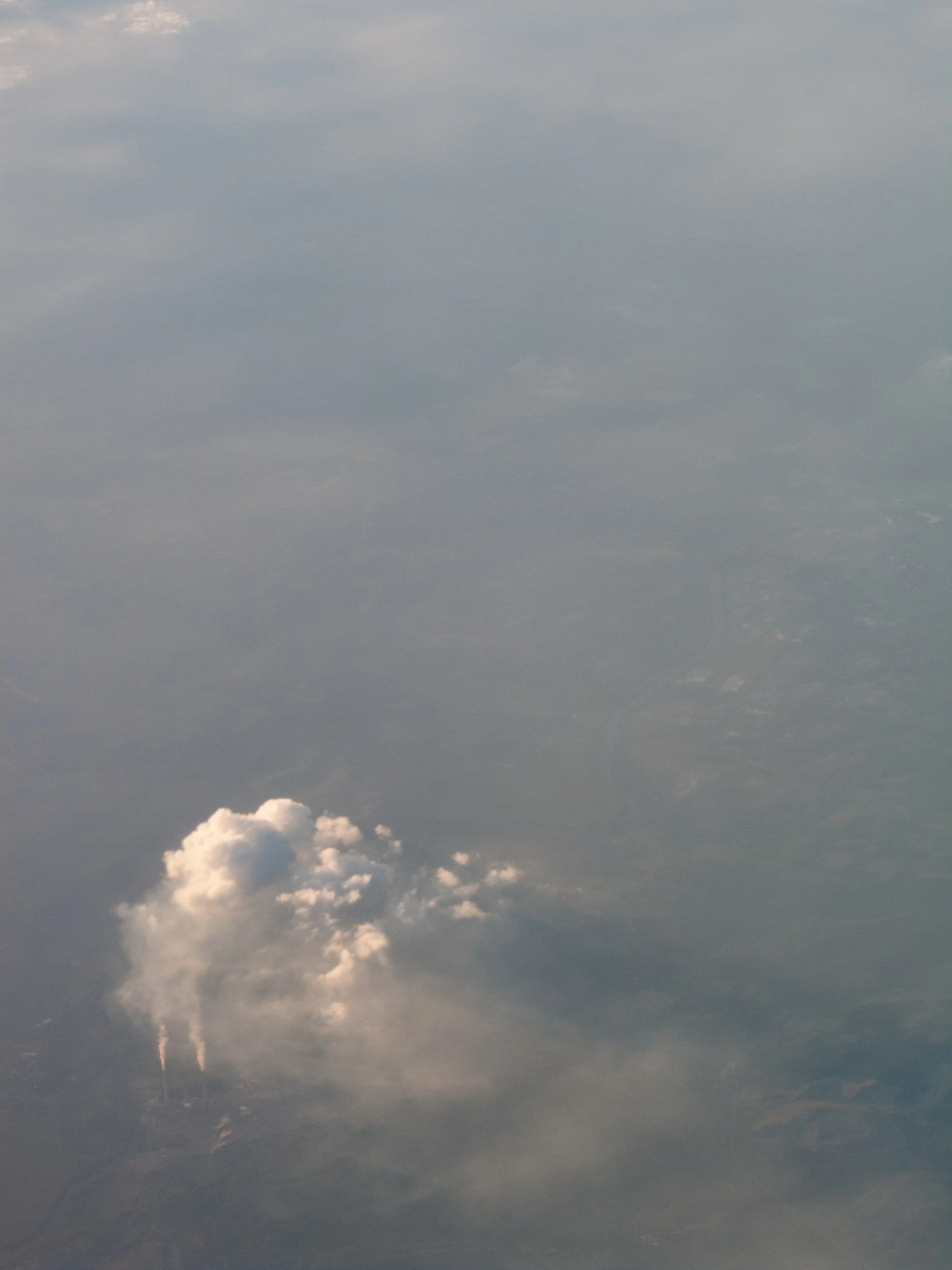 Aerial view of a cloud with two smoke streams rising from the ground below.