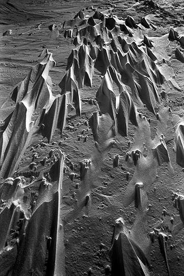 Close-up of sand dunes with sharp, jagged edges in black and white.
