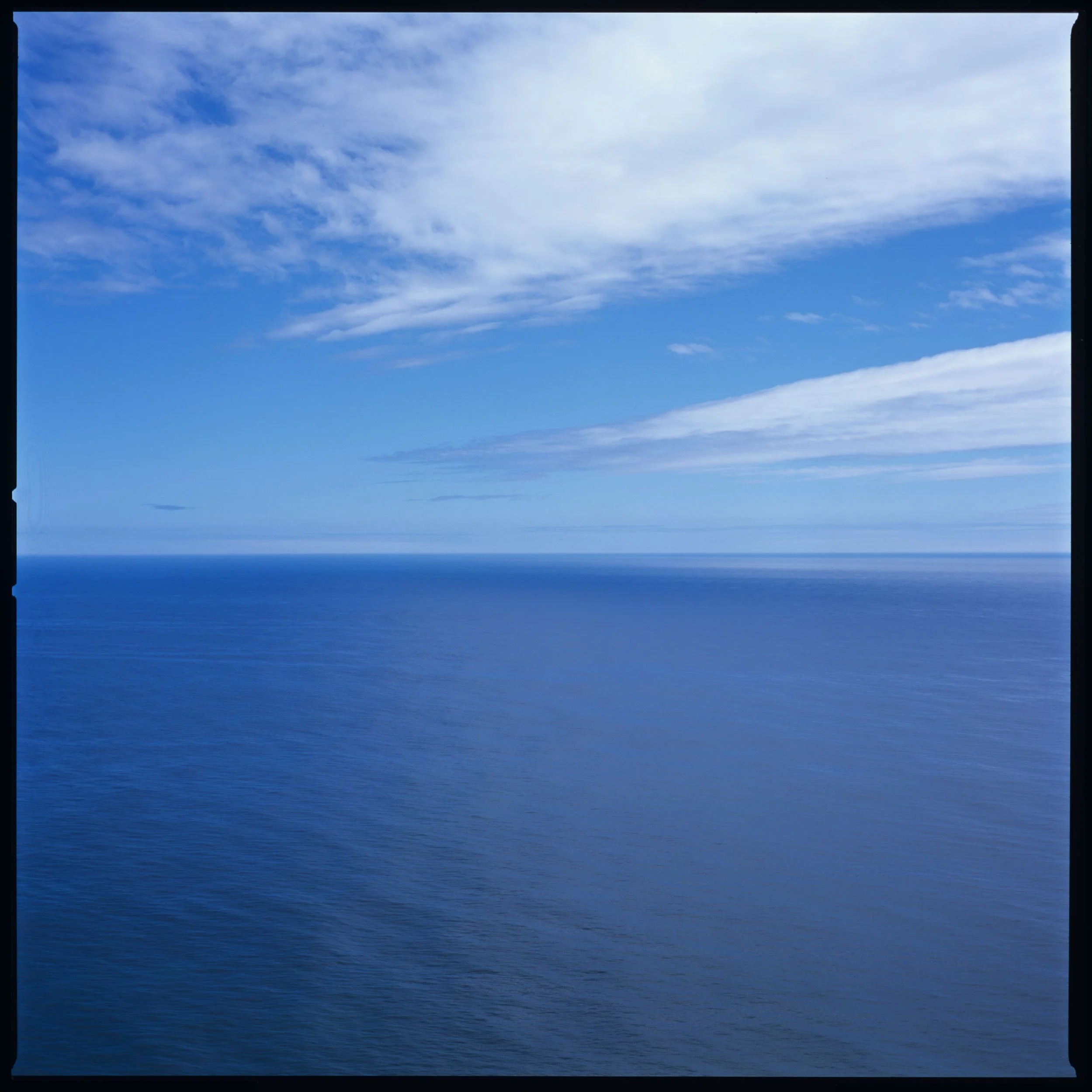 View of the ocean with a blue sky and scattered clouds.