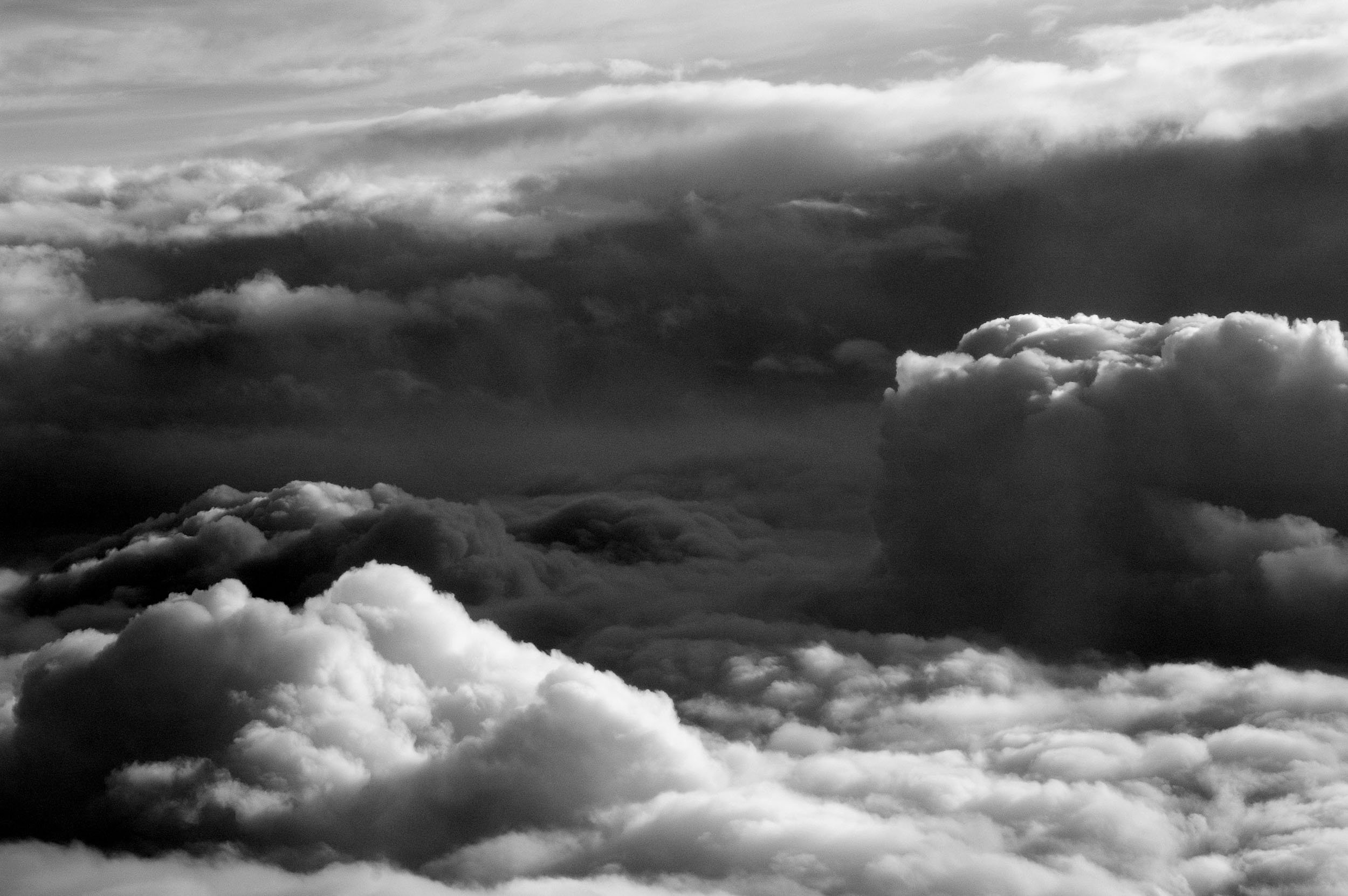 Black and white photo of dark, cloudy sky with various cloud formations at different altitudes.