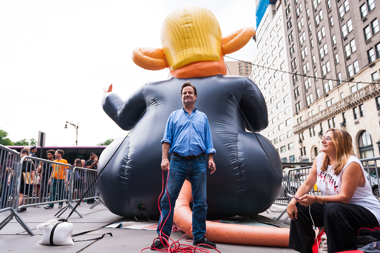 John Lee and Karin Bravin, the gallery owners behind Trump Rat, literally behind Trump Rat. Photographed August Monday, August 14th, 2017 at Grand Army Plaza, NYC, by Jason Woodruff.