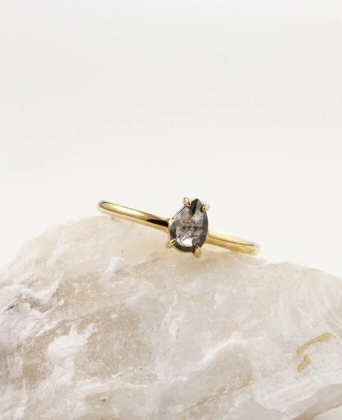 Pear shaped Salt and Pepper diamond, the claw setting is low, close to the finger.