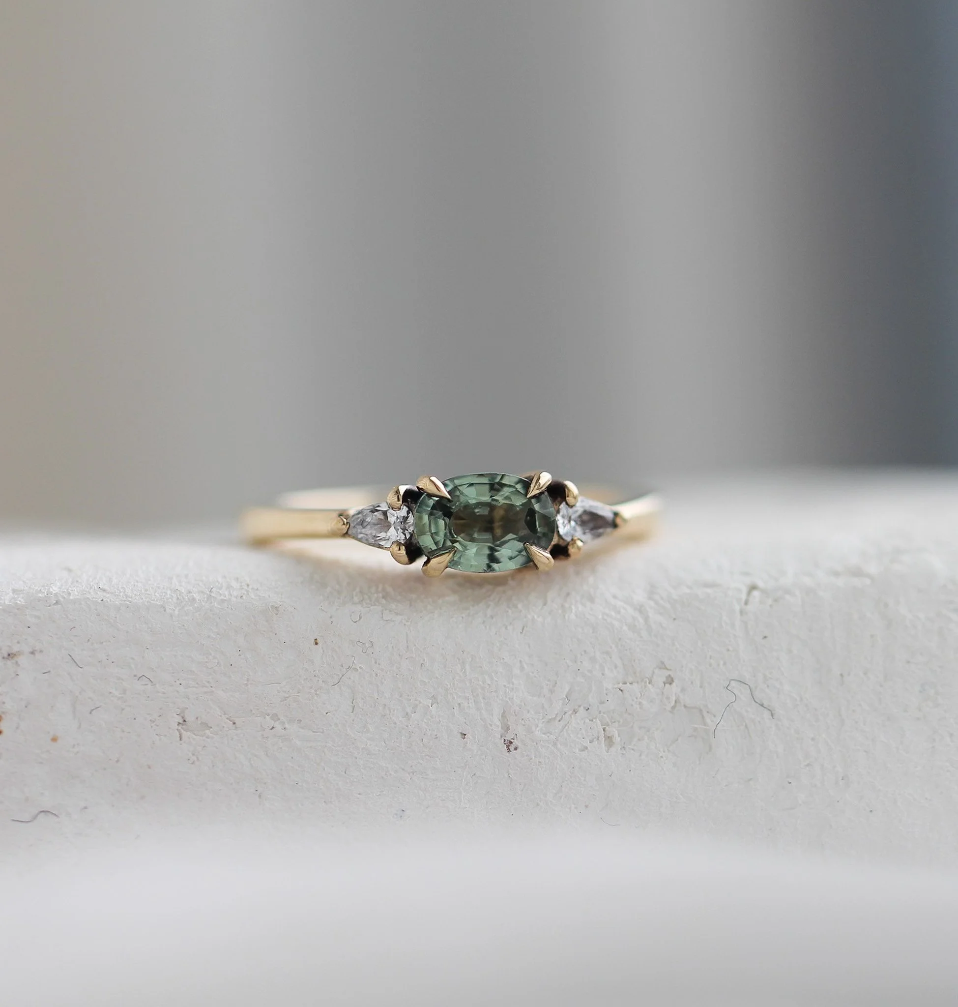 Oval sapphire set east to west, with pear shaped diamond side stones.