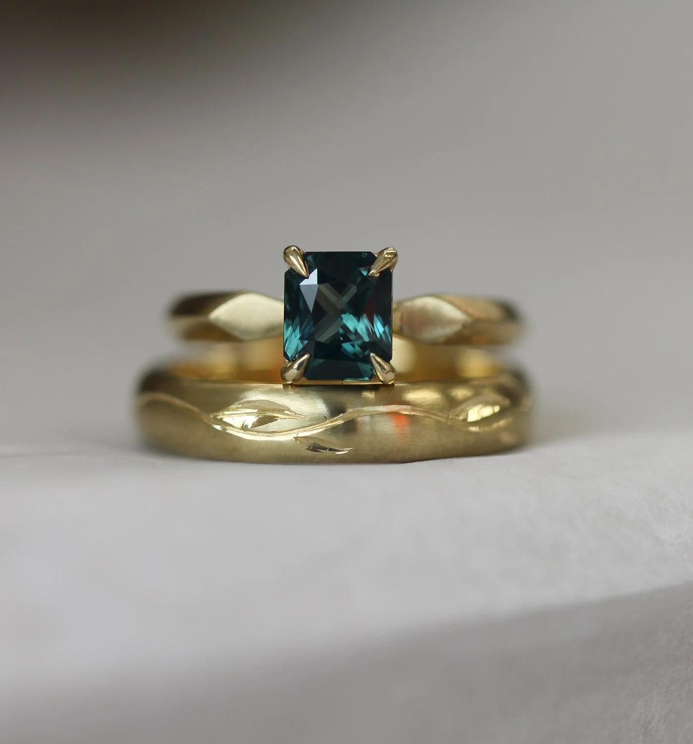 Teal sapphire, on our Hester band. The wedding band has an engraved leaf motif