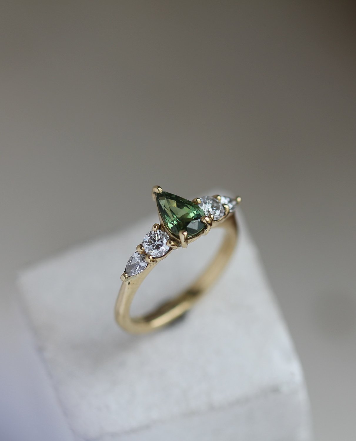 Green pear shaped sapphire, with round and pear diamond side stones.