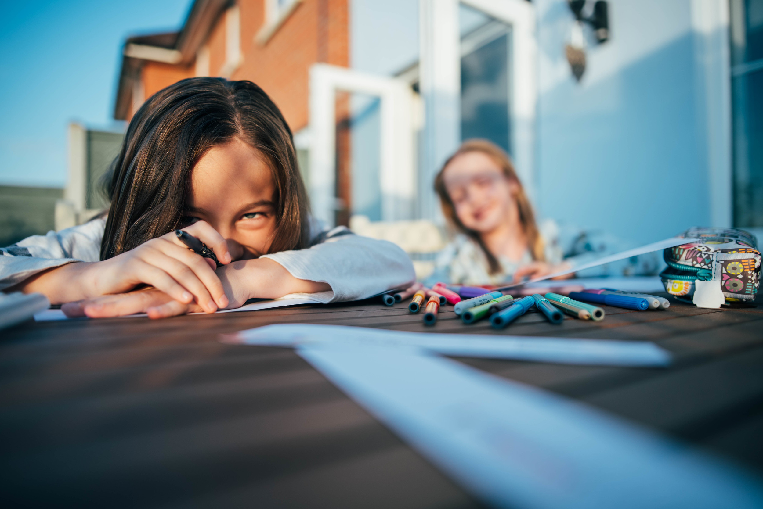 Two girls draw at outside table Essex UK Documentary Portrait and Lifestyle Photographer