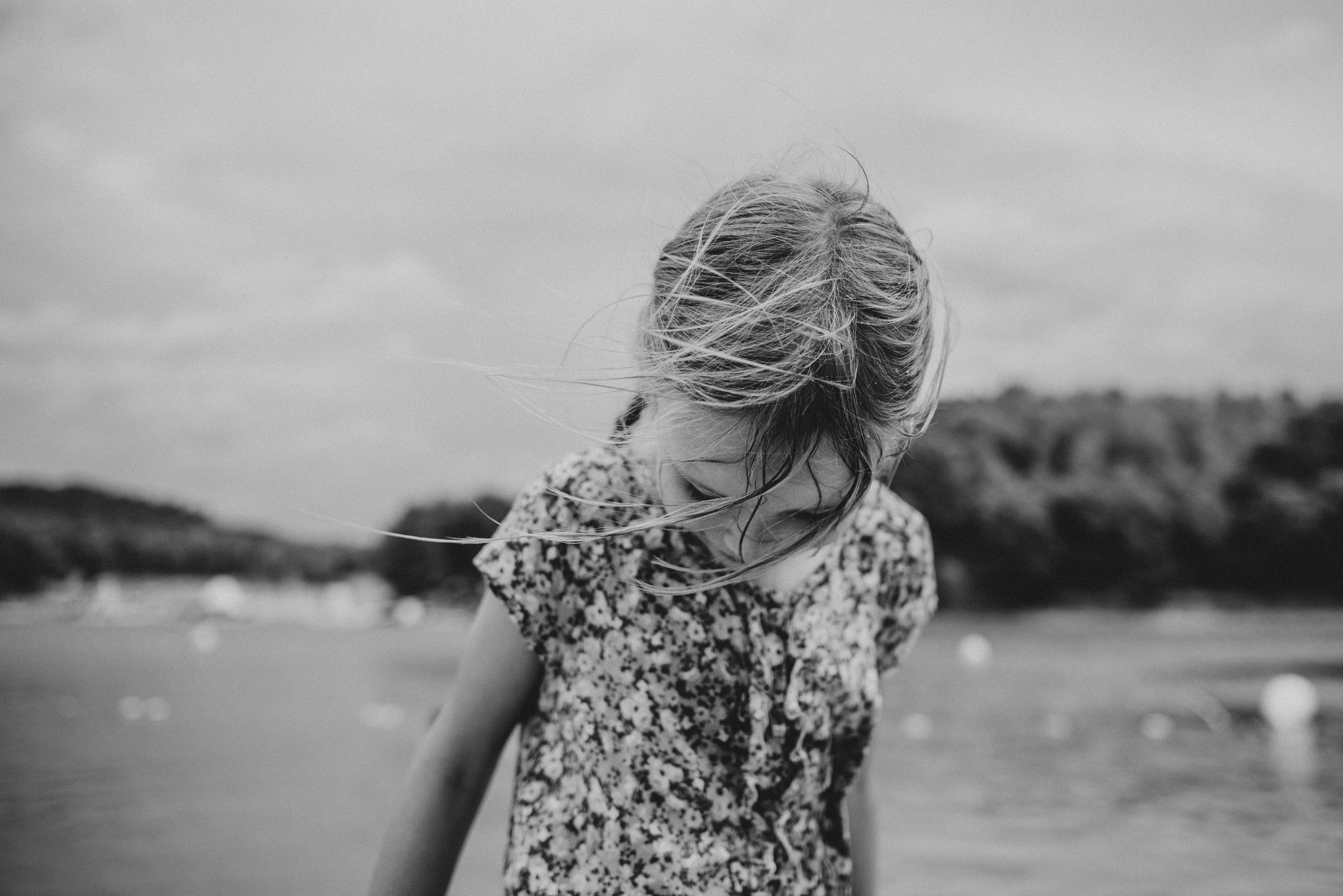 Young girl looks down as she walks out of a lake Essex UK Documentary Portrait Photographer