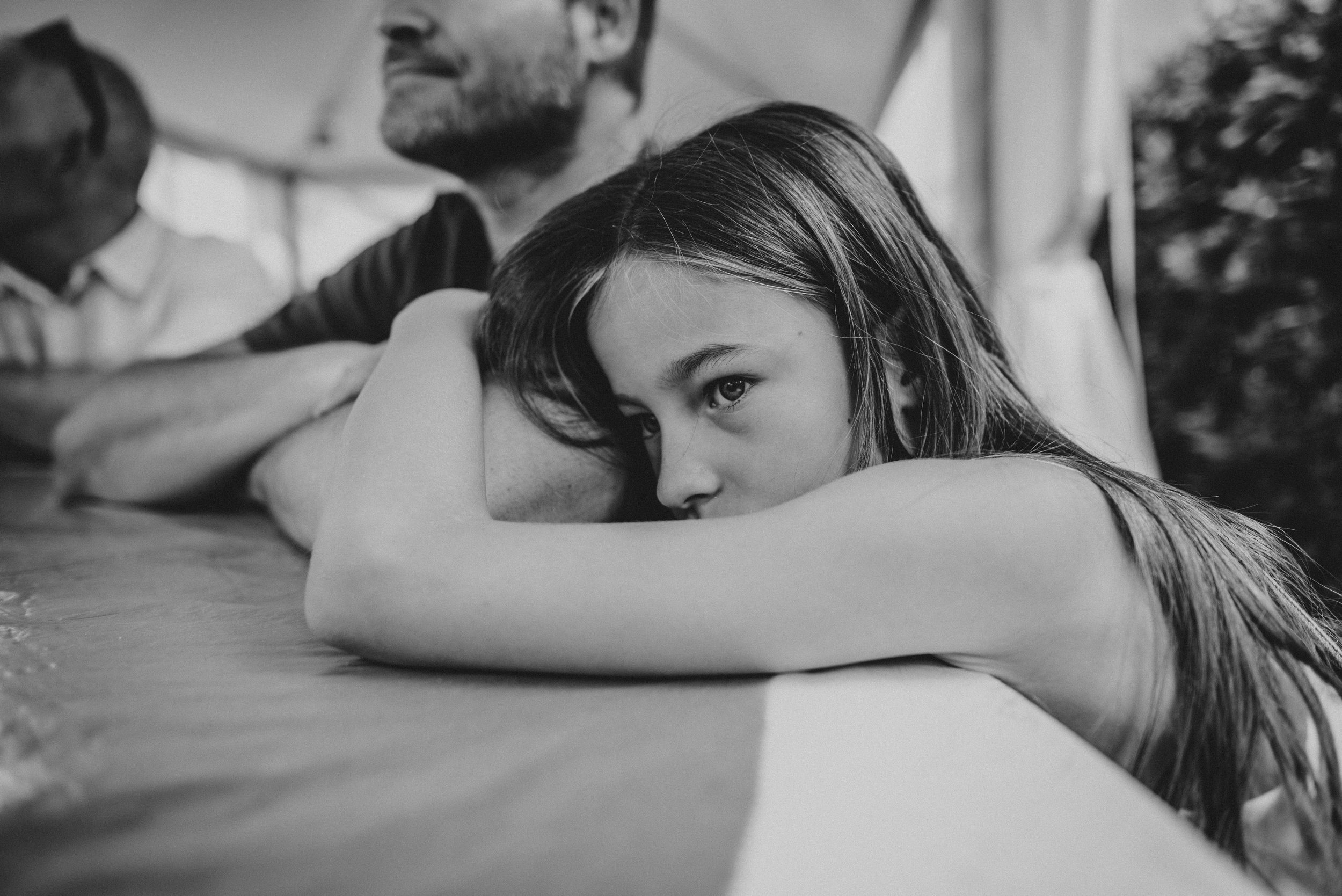 Little girl hugs Dads arm Essex UK Documentary Portrait Photographer