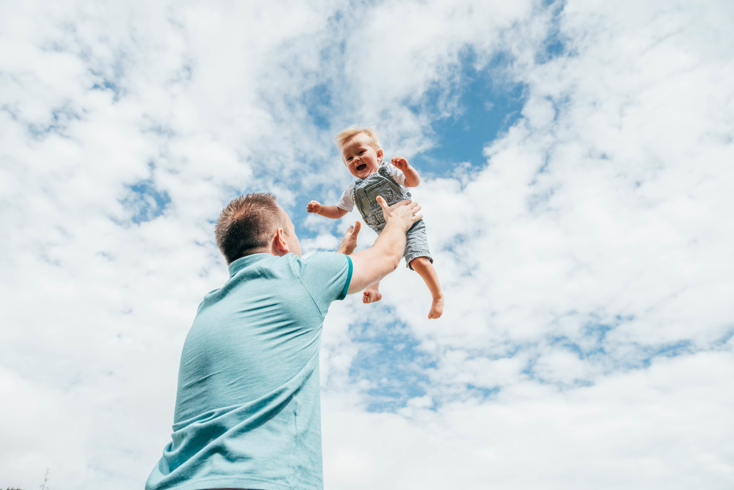 Dad holds baby boy up to the sky Essex UK Documentary Portrait Photographer