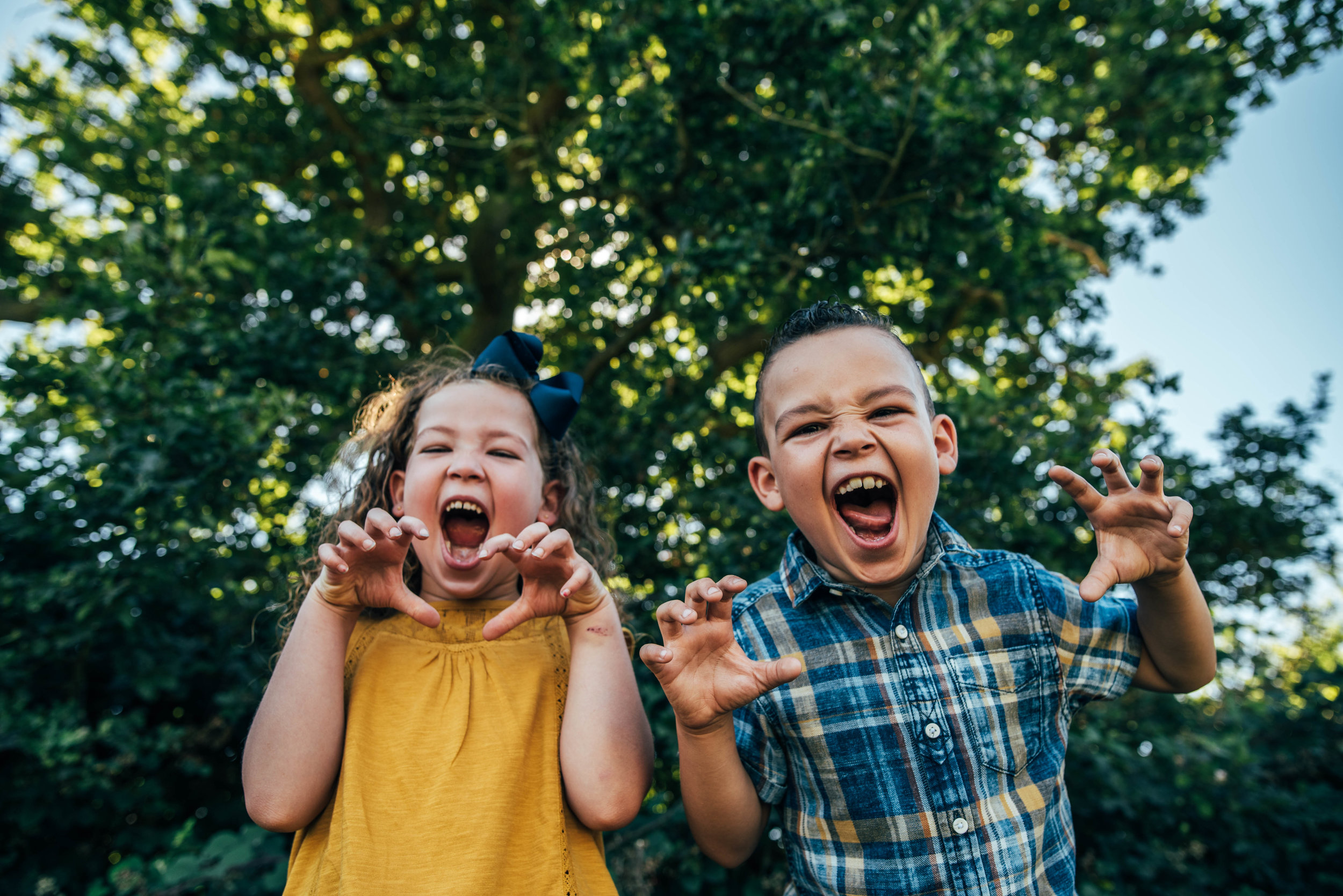 Brother and Sister make faces into camera Essex UK Natural Documentary Portrait Photographer