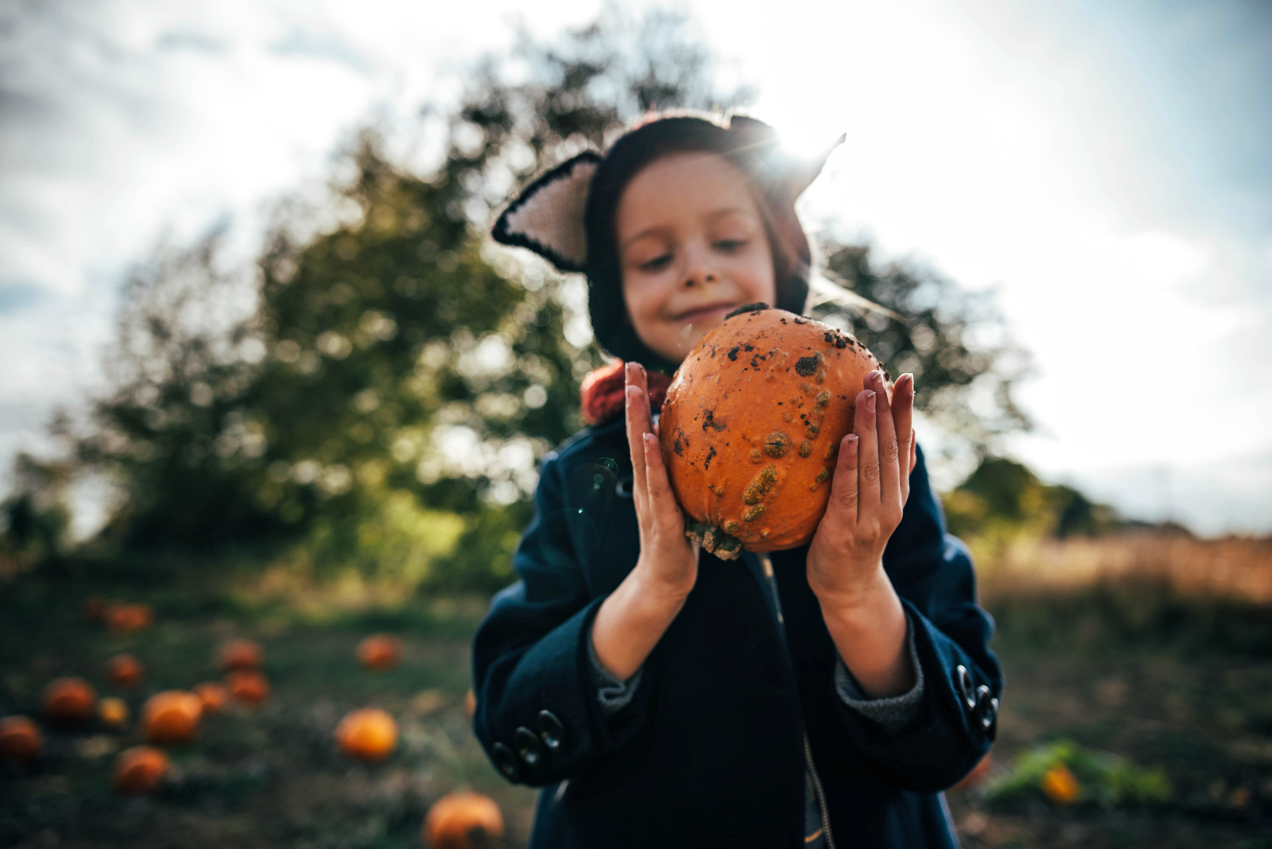 Little girl in Fox hat holds Pumpkin Essex UK Documentary Portrait Photographer