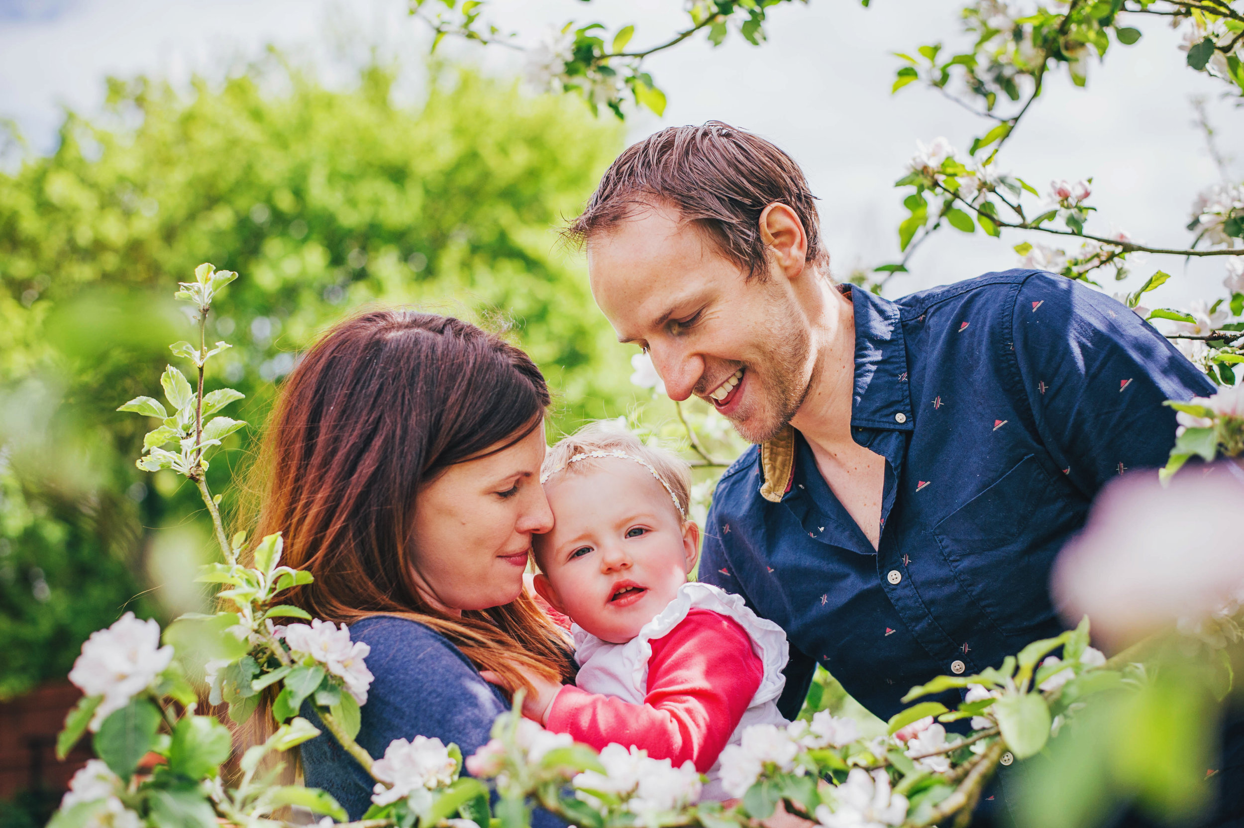 Mum and Dad with baby girl in Blossom At Home Lifestyle Shoot Essex UK Documentary Portrait Photographer
