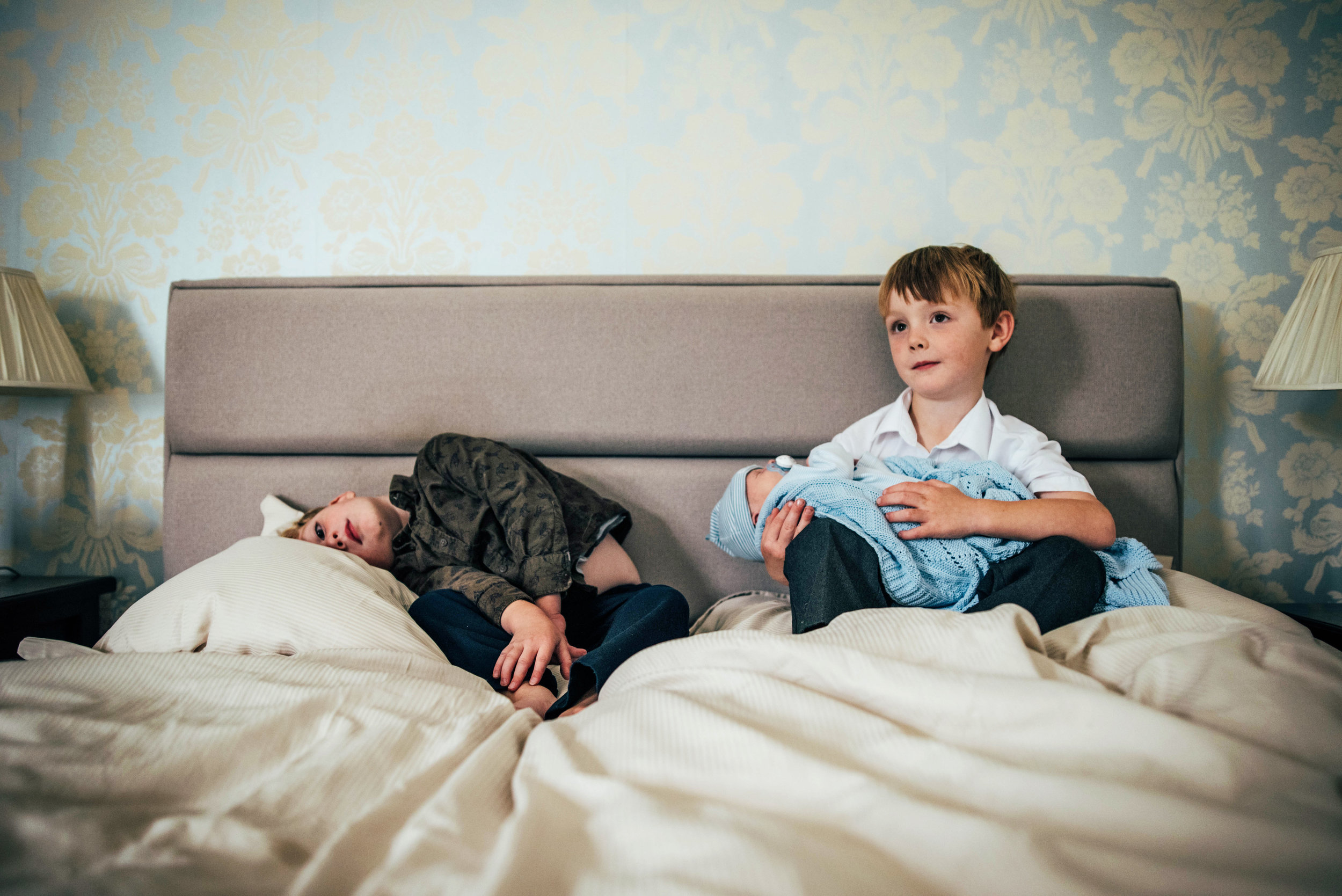 Two boys with new brother on bed At Home Lifestyle Shoot Essex UK documentary Portrait Photographer 