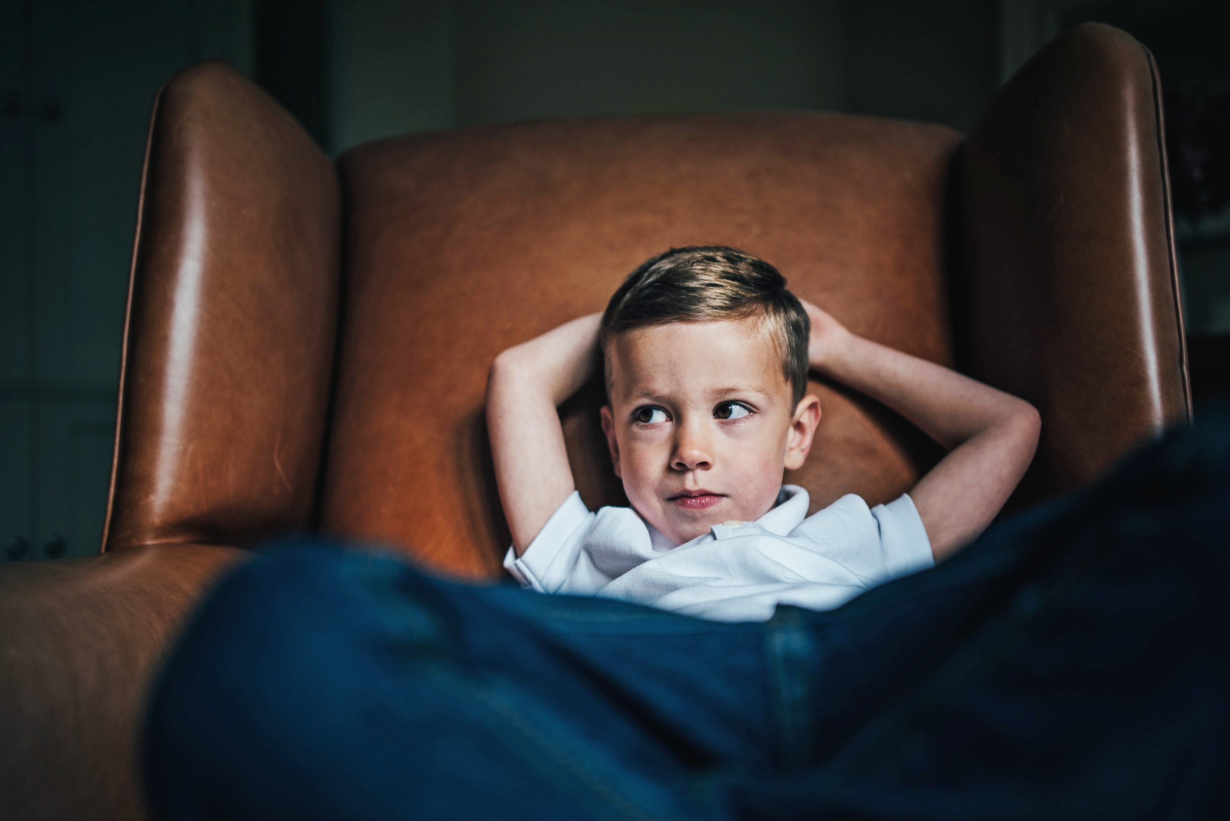 Grumpy boy in wingback chair At Home Lifestyle Shoot Essex UK Documentary Portrait Photographer 