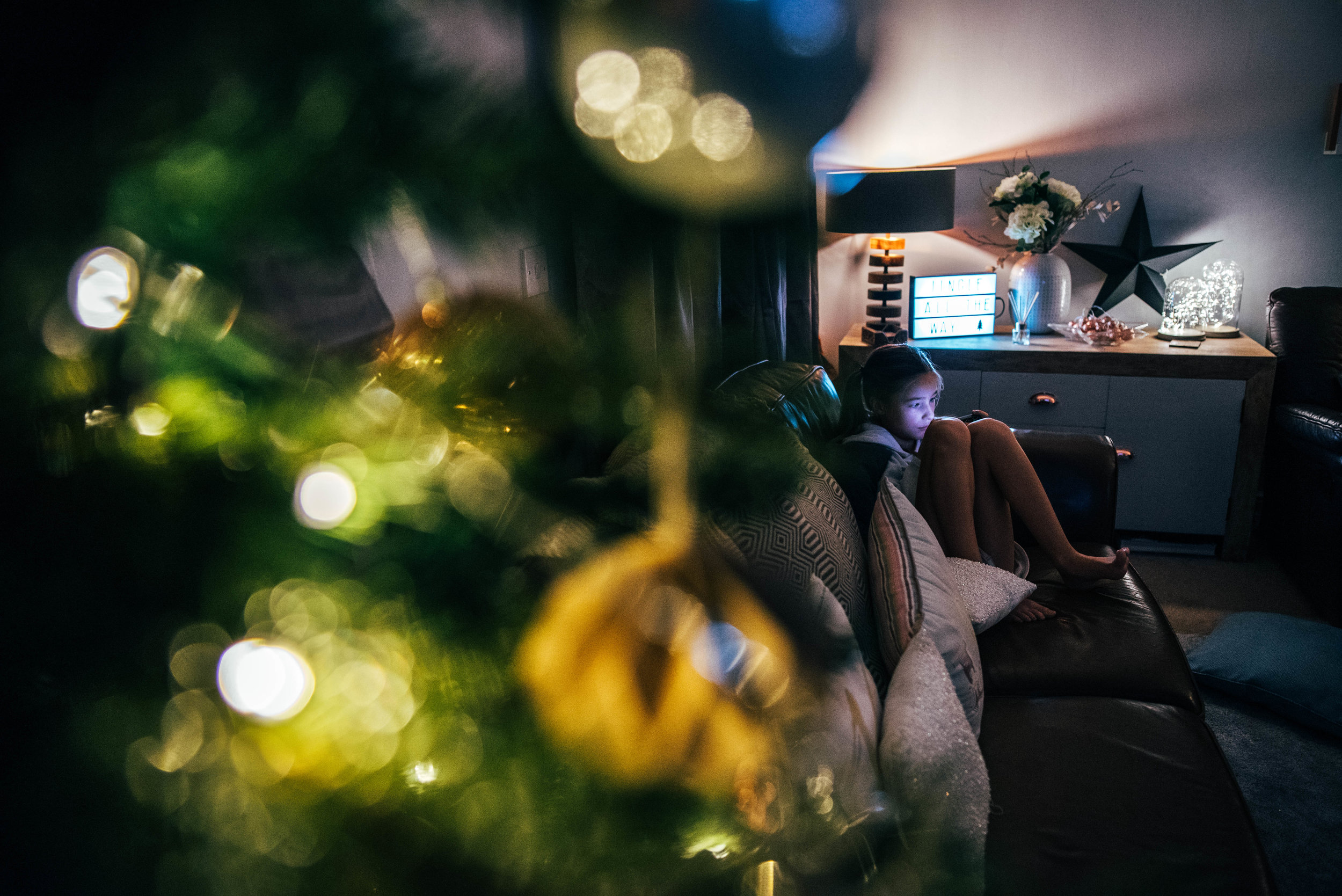 Little girl looks at iPad by a christmas tree Essex UK Documentary Photographer