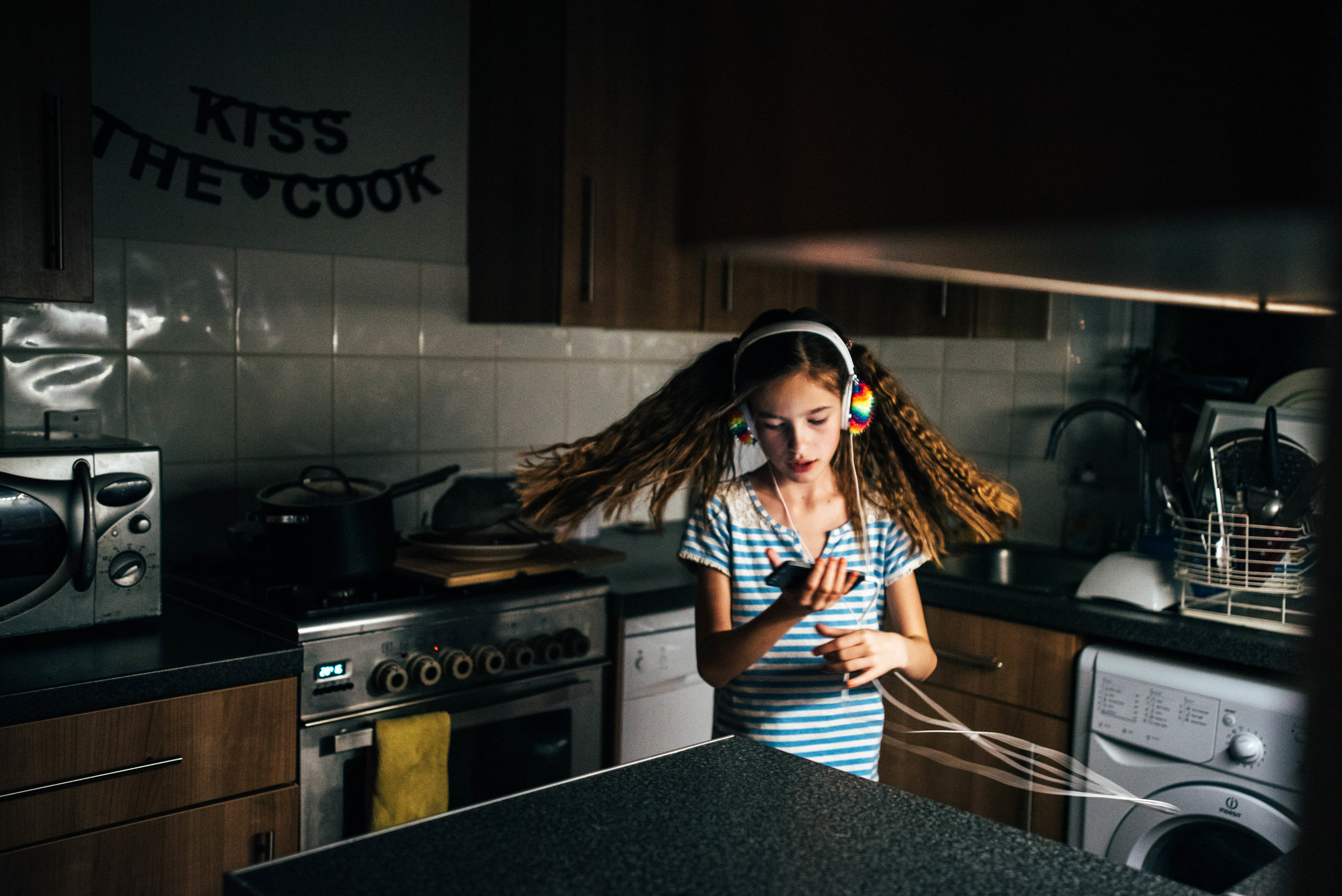 Tween girl dances with headphones in kitchen Essex UK Documentary Portrait Photographer 