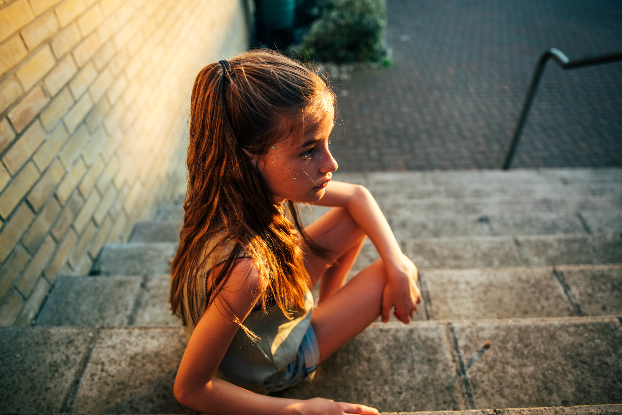 Young girl sits on steps in sunset Essex UK Documentary Portrait Photographer 