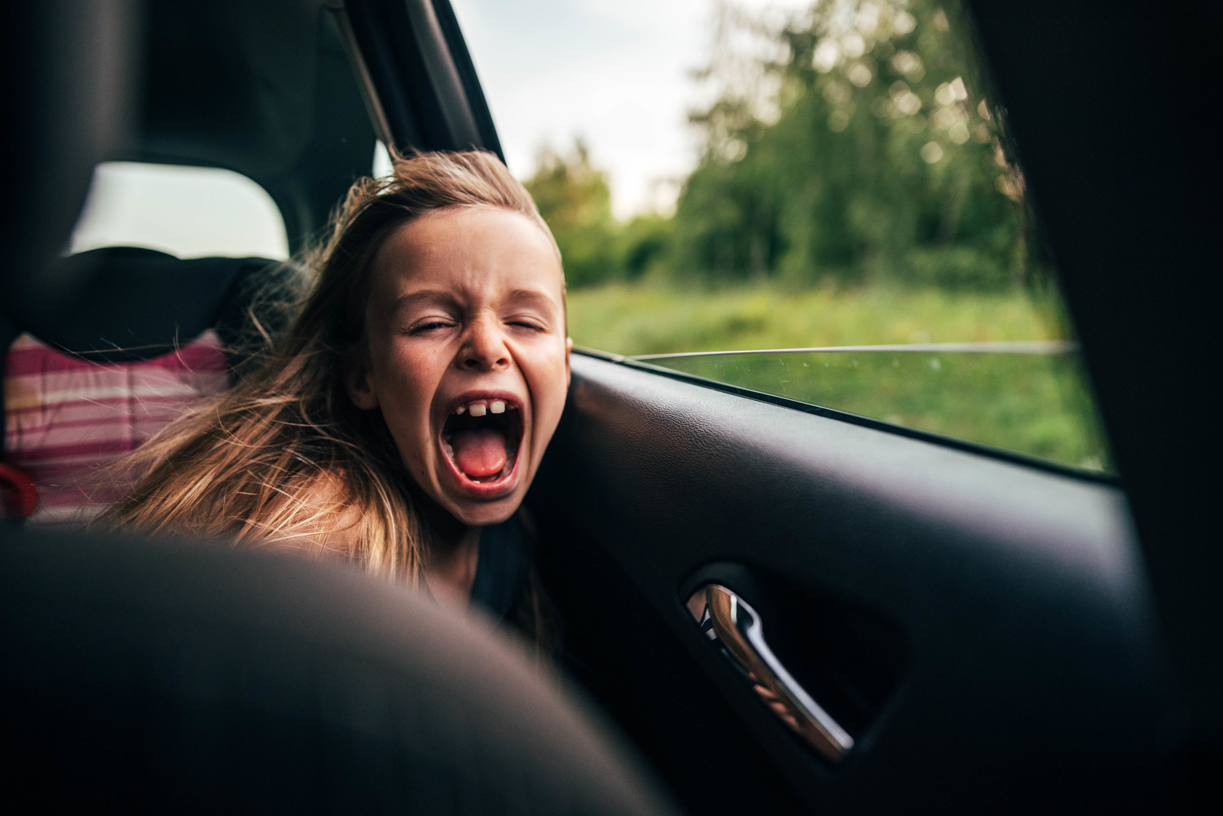 Young girl enjoys breeze in back of car Essex UK Documentary Portrait Photographer