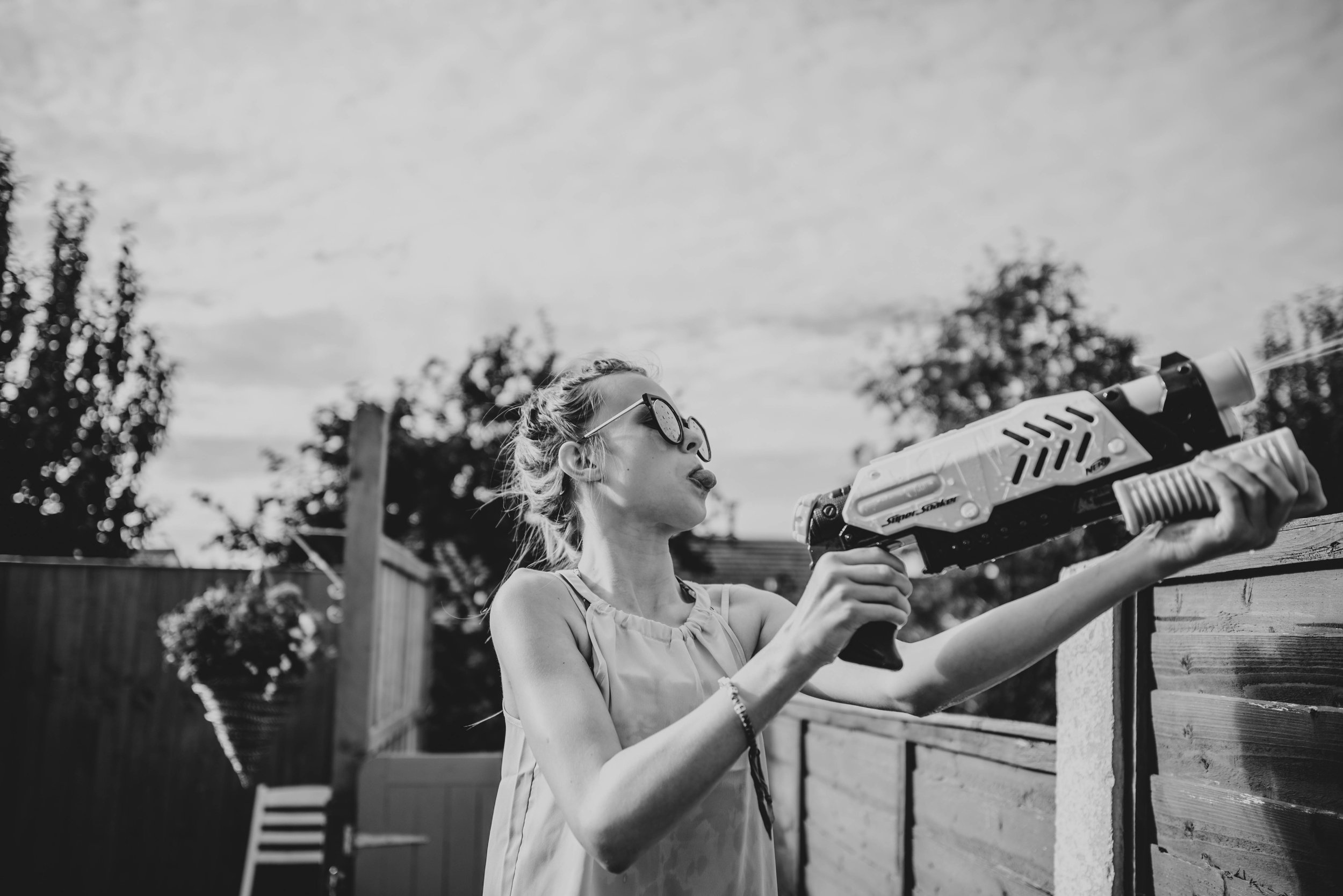 teen girl shoots water pistol over fence Essex UK Documentary Portrait Photographer