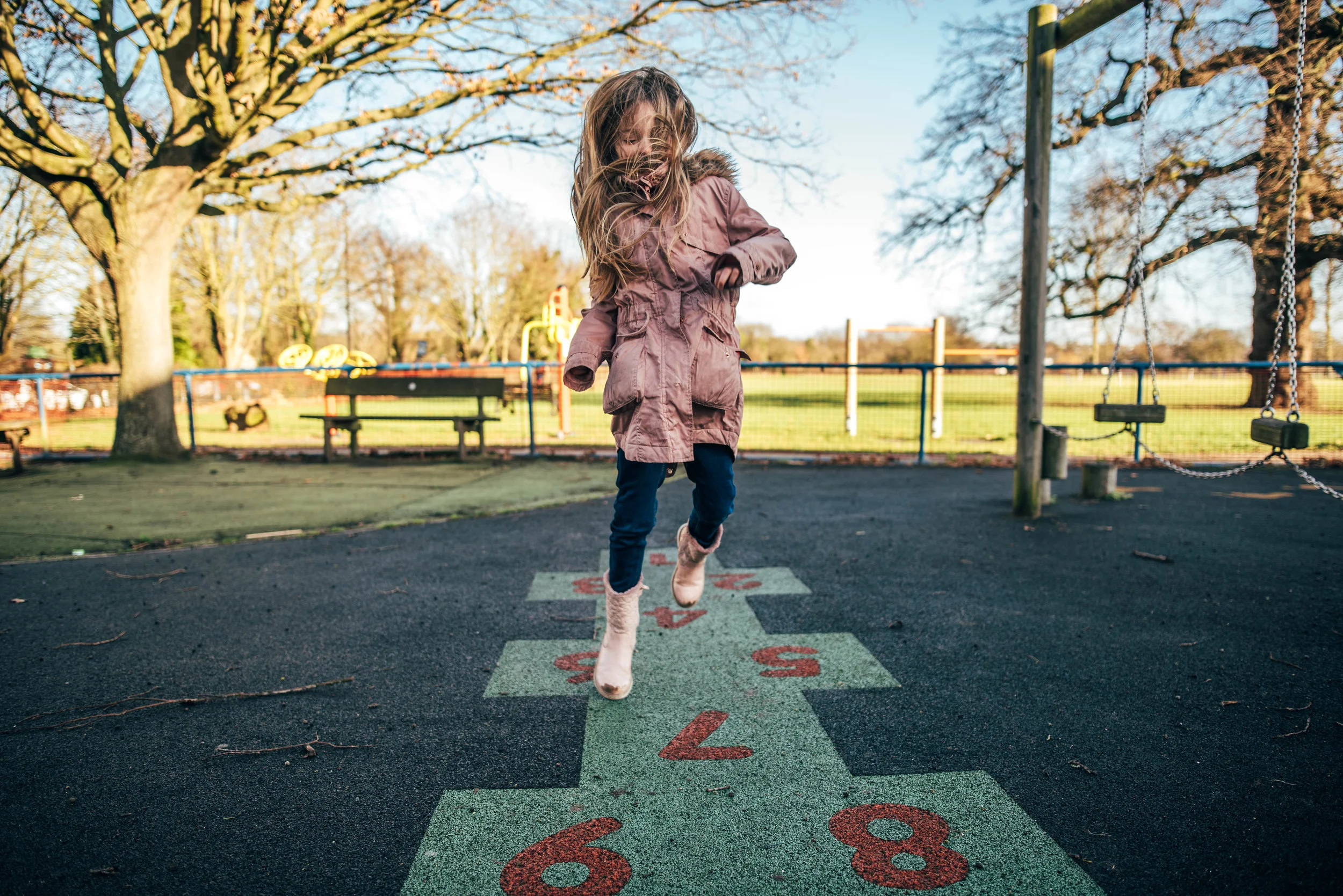 Girl plays hopscotch in winter park Essex UK Wedding Documentary Photographer