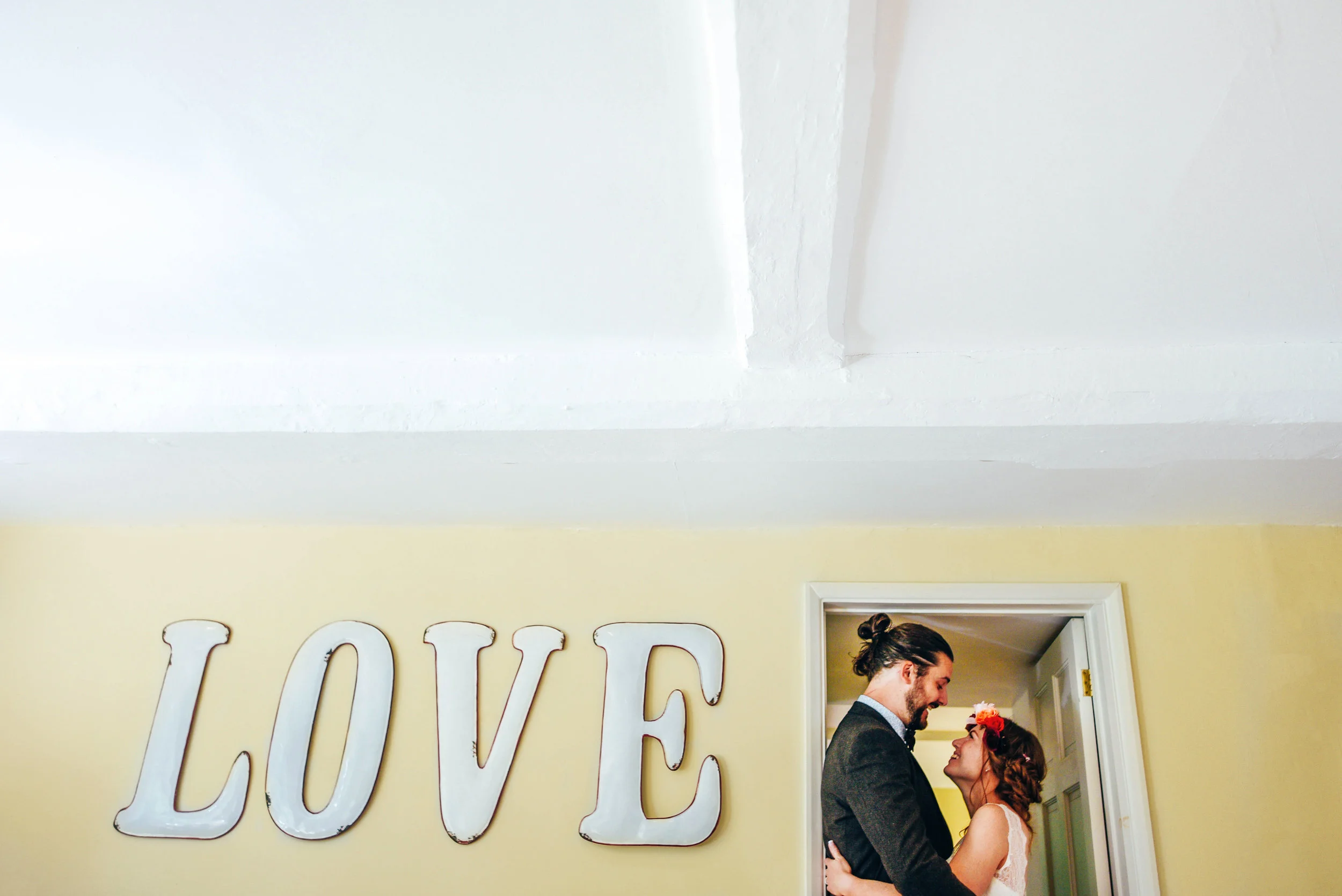 Couple in doorway with LOVE Houchins Essex Documentary Wedding Photographer