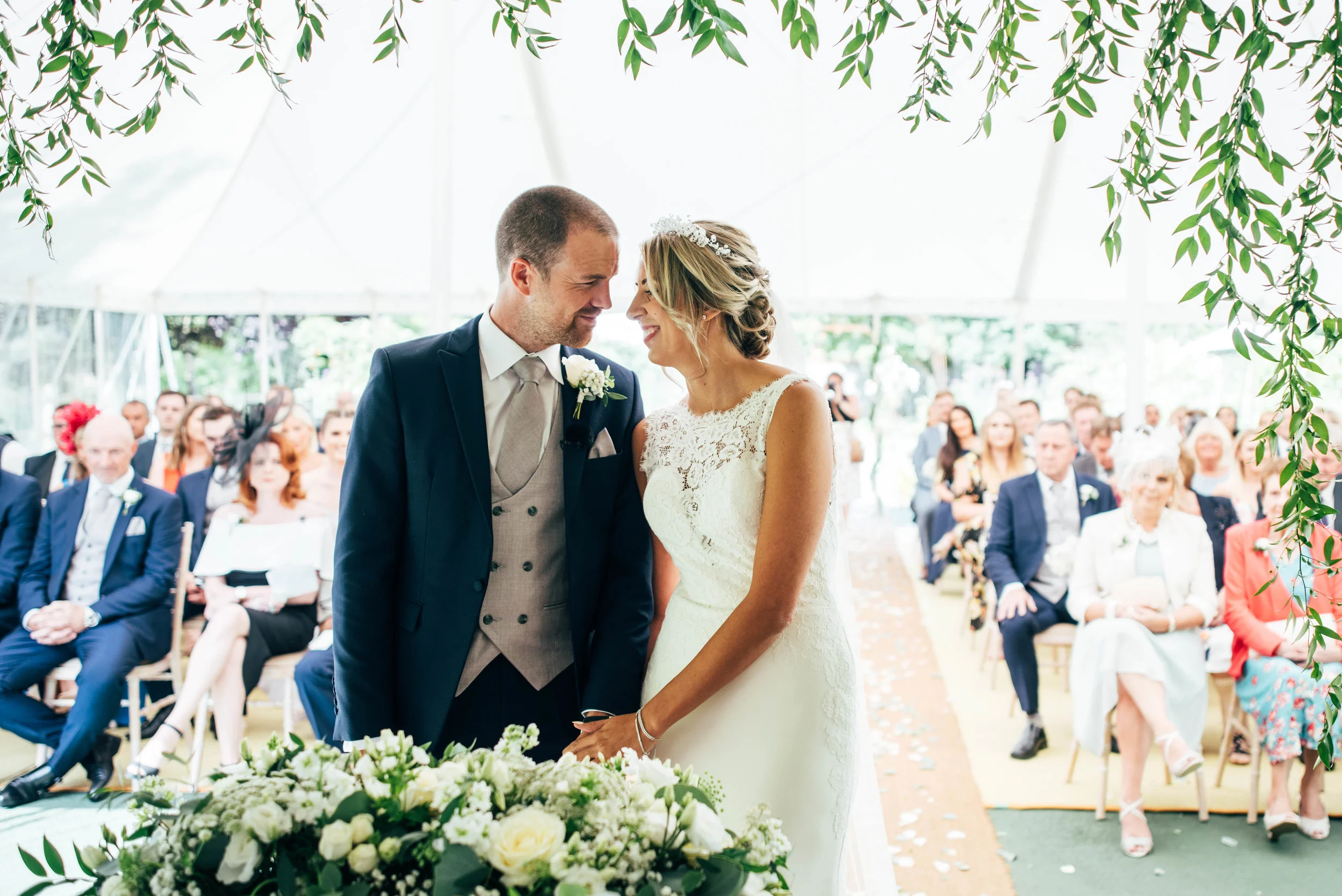 Bride and Groom smile at each other during ceremony at Houchins Farm, Coggeshall, Essex Documentary Wedding Photographer