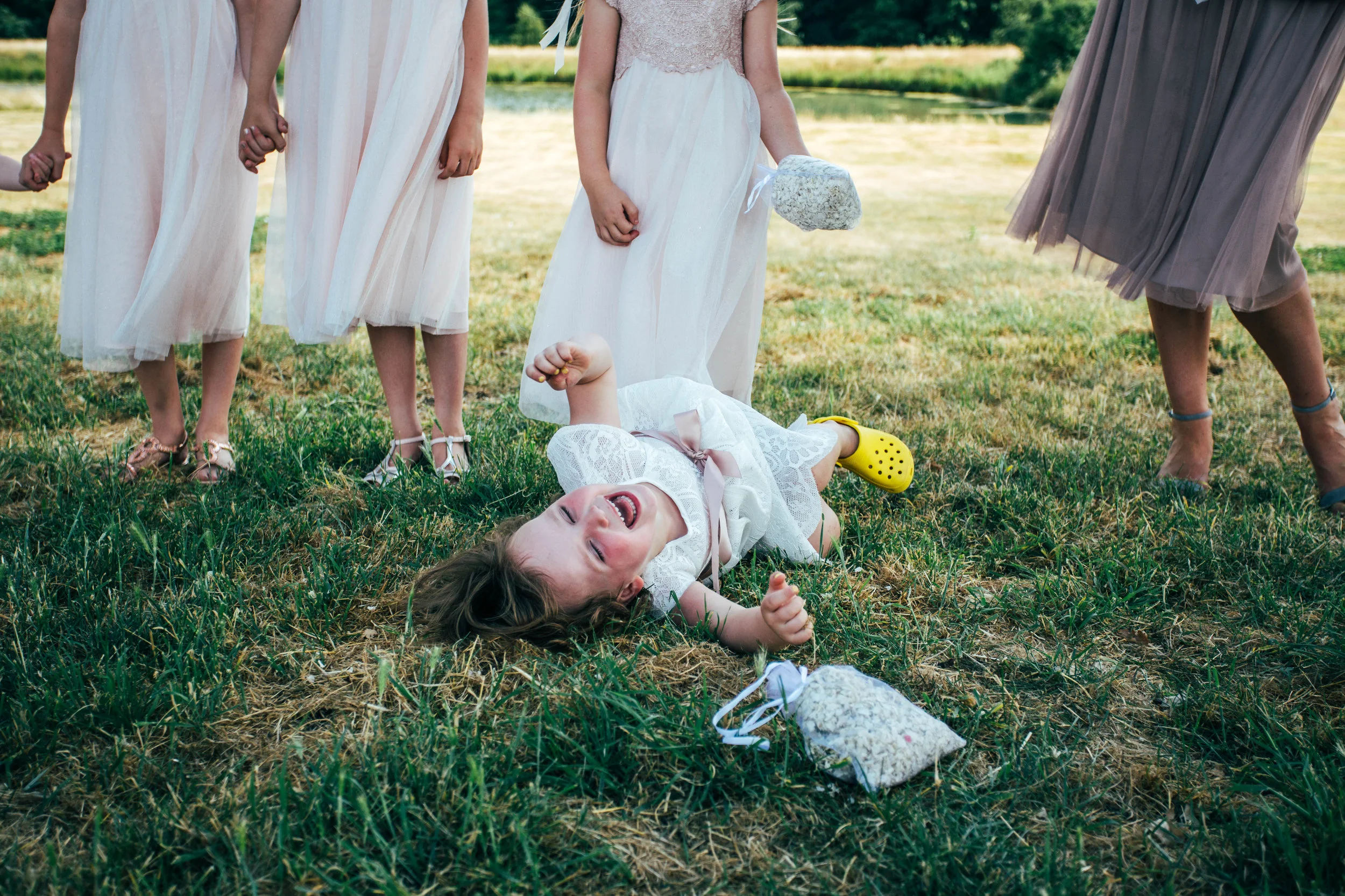 Flower Girl laughs on floor for DIY Back Garden Wedding Essex Documentary Wedding Photographer