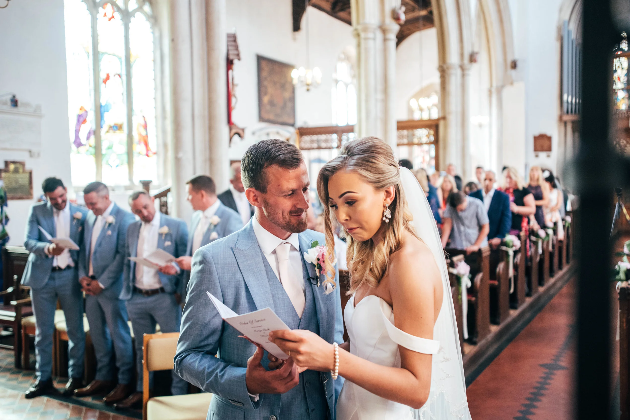 Groom steals a look at his Bride at St Marys Church, Bocking for Fennes, Braintree Wedding.  Essex Documentary Wedding Photographer