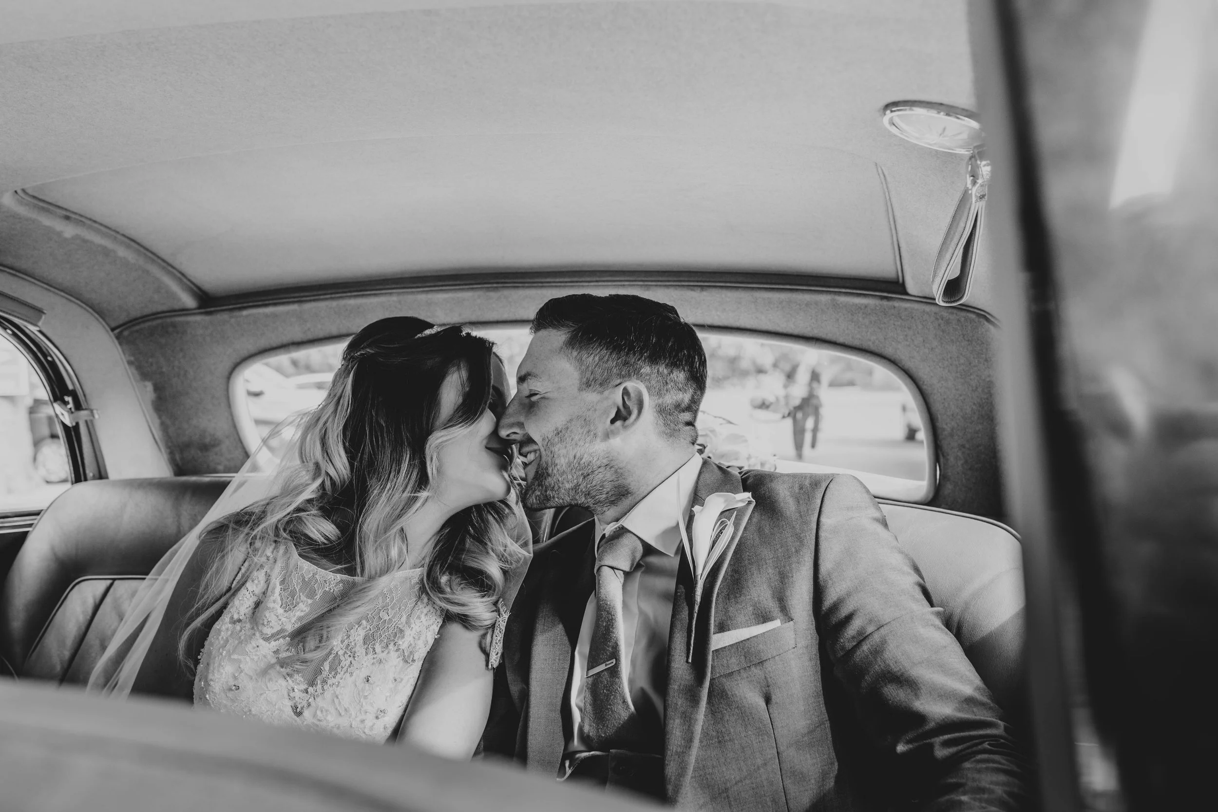 Bride and Groom kiss in back of wedding car at Blake Hall, Ongar.   Essex Documentary Wedding Photographer
