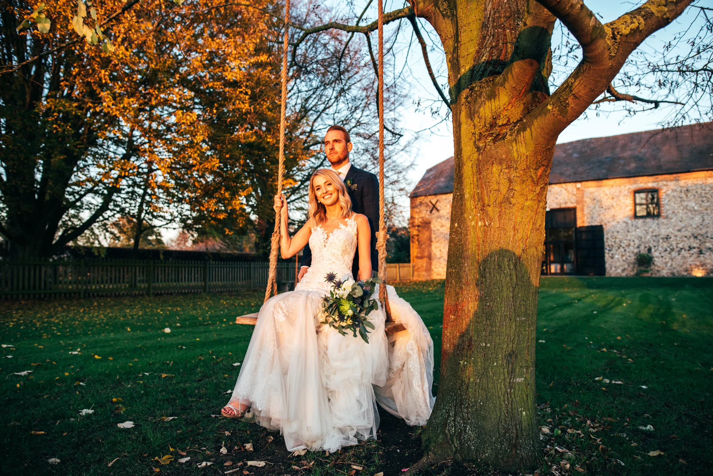 Groom pushes Bride on swing in Autumn sunset wedding at The Granary Estates, Woodditton.  Essex Documentary Wedding Photographer